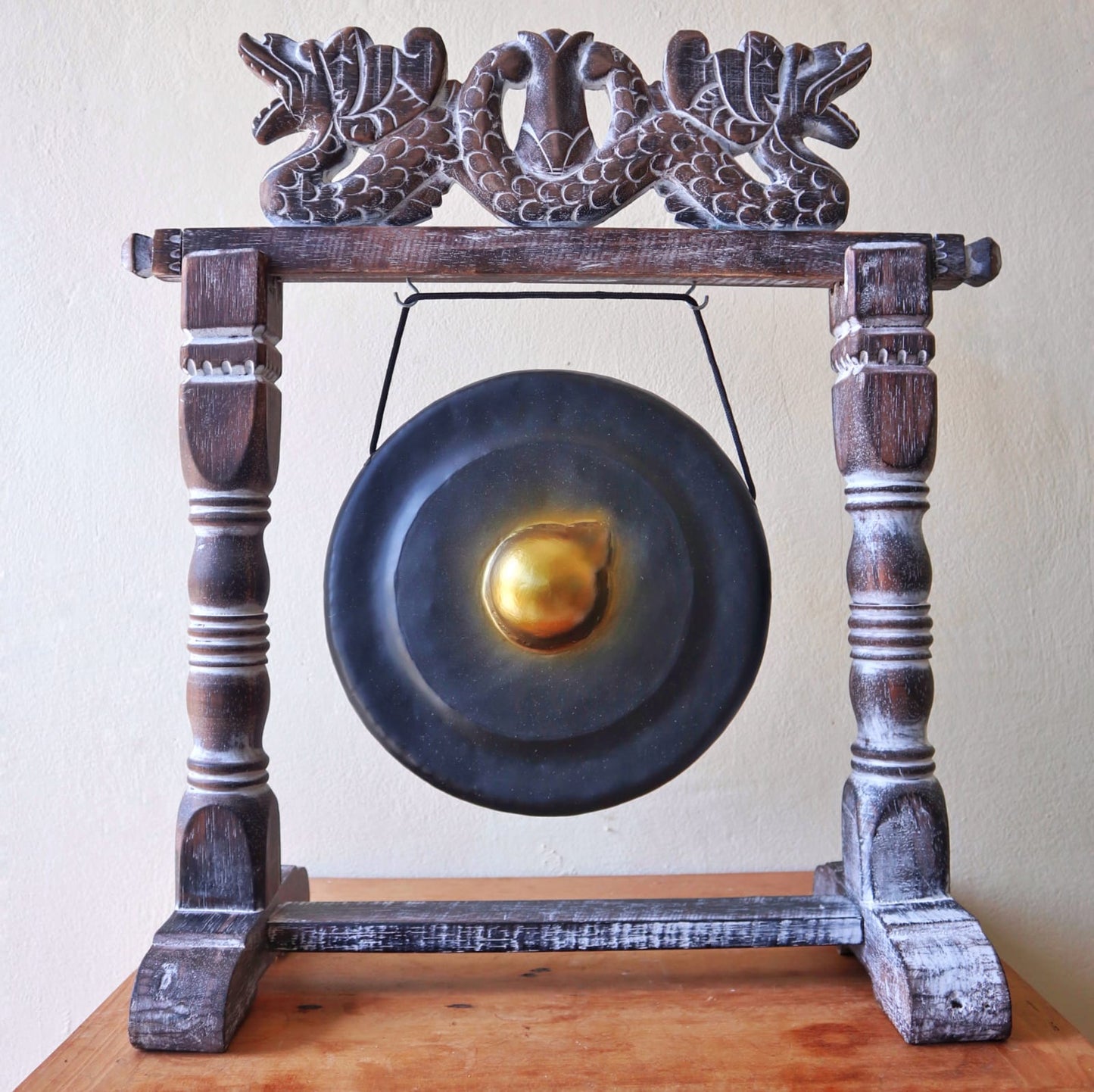 Small 25cm Black Gong - Traditional gong with golden centre, suspended from an ornate wooden frame with carved dragon motifs.