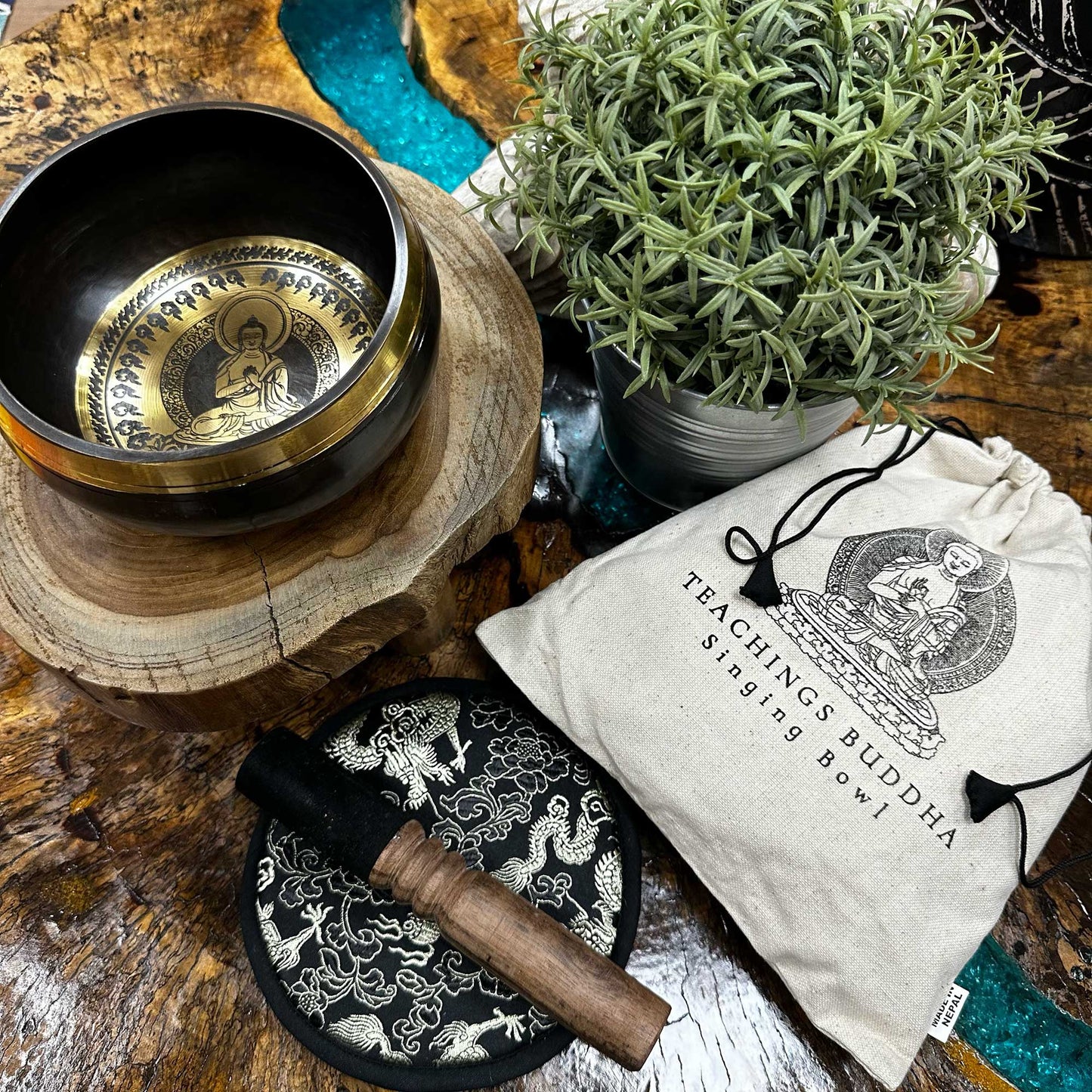 Top View of the 14 cm Hand Beaten & Engraved Singing Bowl Gift Set Sitting on a table surrounded by decorative Spiritual Ornaments.
