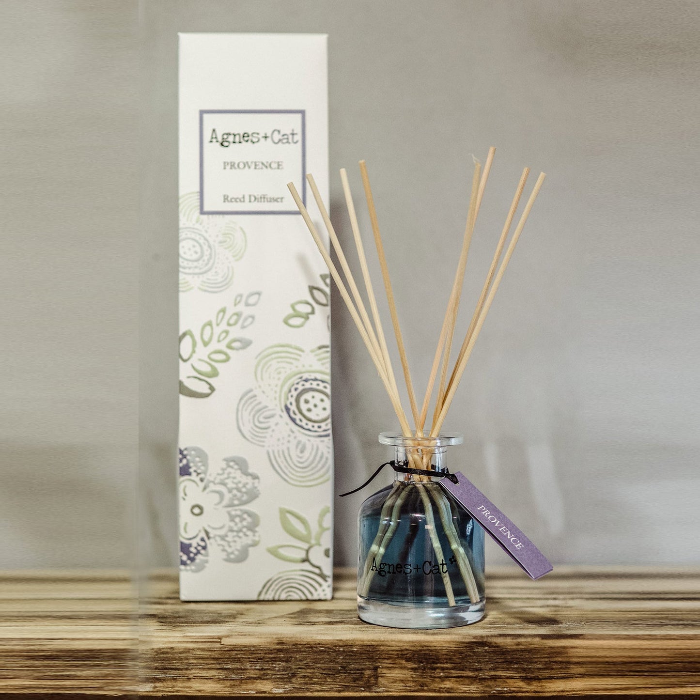 Reed Diffuser - Provence - 140ml, dark blue-tinted bottle with natural-coloured reeds beside a tall illustrated box by Quintessential Holistic Health Ltd