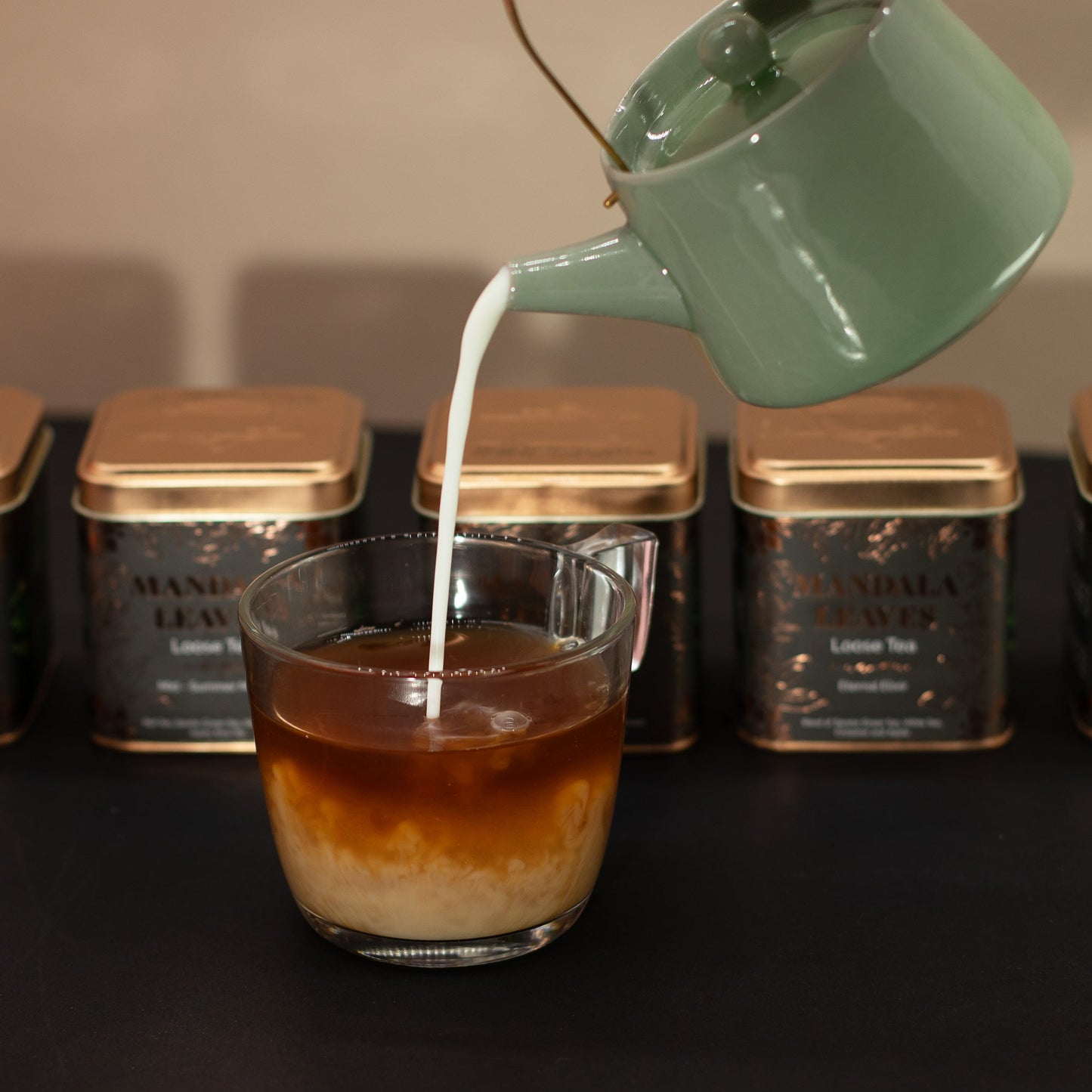 Green Dragon Blend Artisan Tea - Tinned - 50g, pale liquid poured from a green jug into a glass of dark liquid beside three tins by Quintessential Holistic Health Ltd