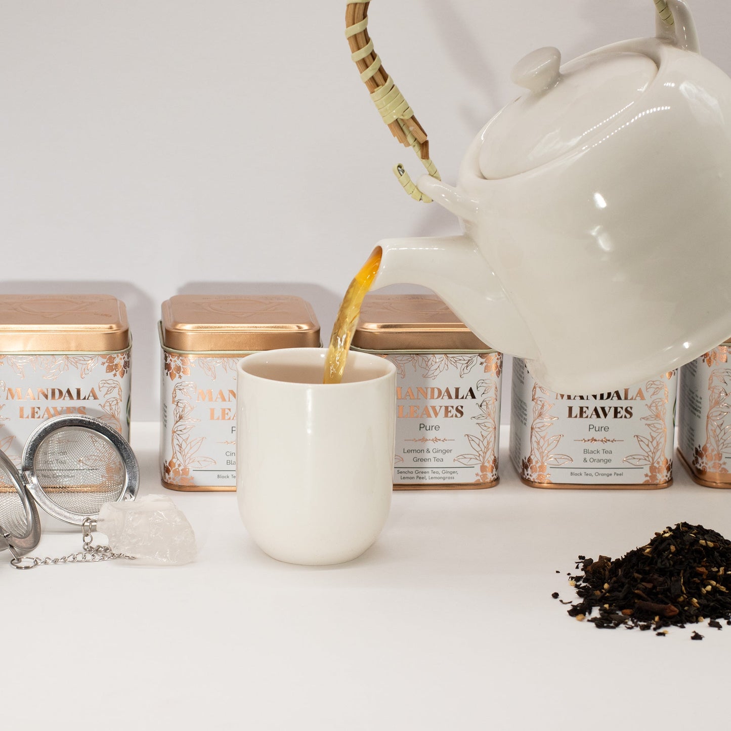 Eco Classic Lemon and Ginger Blend Green Tea - Tinned - 50g, teapot pouring into a cup with tins and loose tea nearby, by Quintessential Holistic Health Ltd