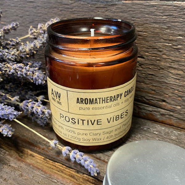 Soy Wax Candle - Positive Vibes - Clary Sage & Peppermint, lit in an open amber jar beside lavender stems by Quintessential Holistic Health Ltd