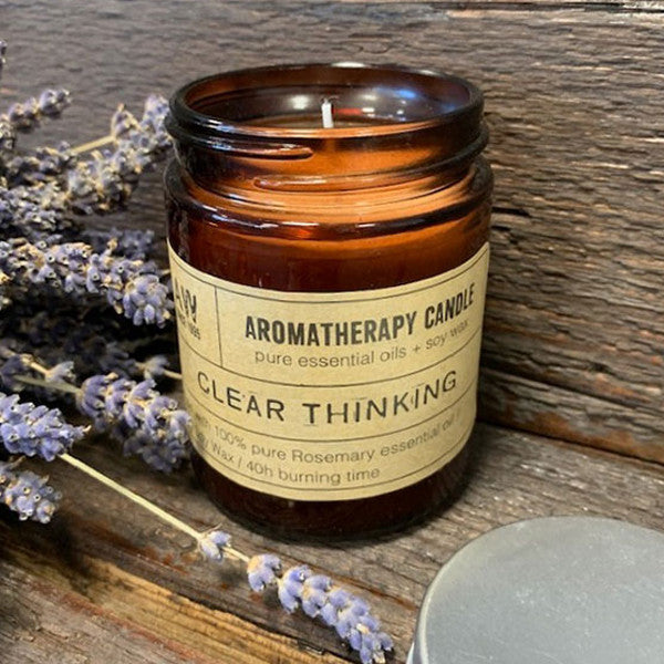 Soy Wax Candle - Clear Thinking - Rosemary, lit in an open amber jar beside lavender stems by Quintessential Holistic Health Ltd