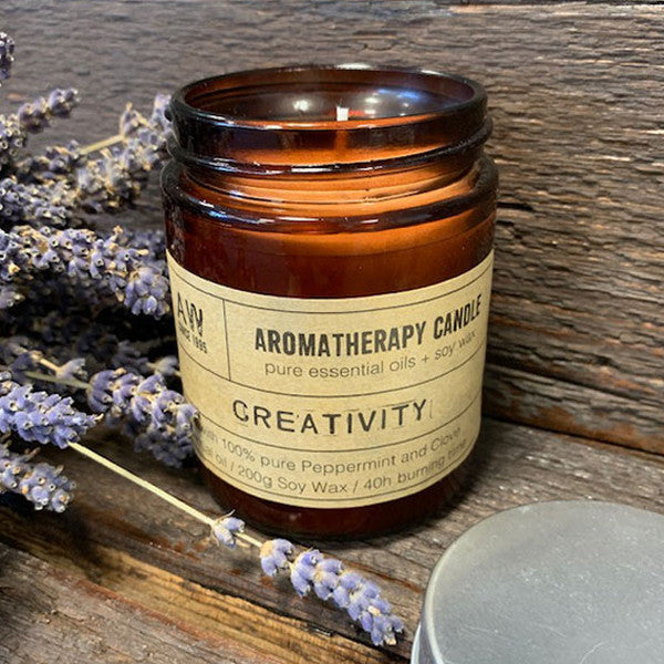 Soy Wax Candle - Creativity - Peppermint & Clove, lit in an open amber jar beside lavender stems by Quintessential Holistic Health Ltd