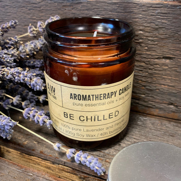 Soy Wax Candle - Be Chilled - Lavender & Fennel, lit in an open amber jar beside lavender stems by Quintessential Holistic Health Ltd