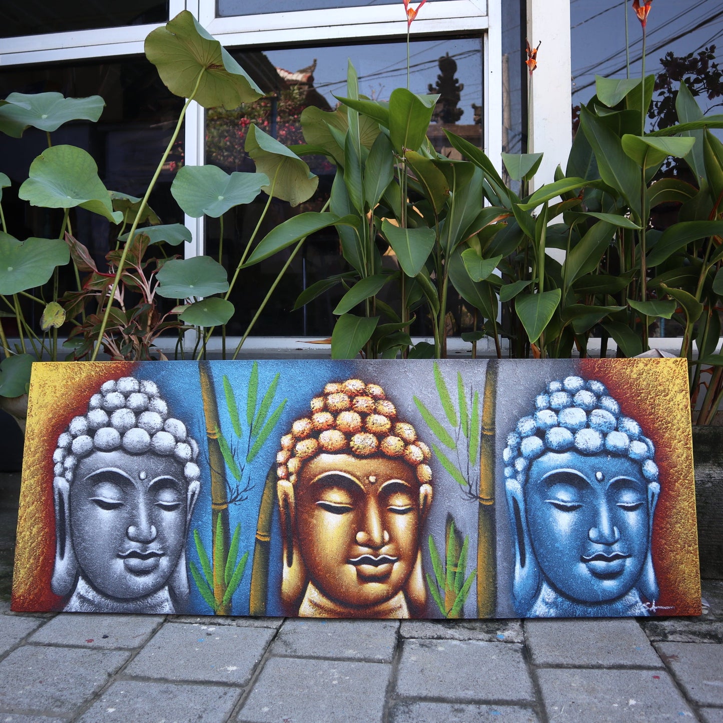 Hand Painted Buddha Painting - Bamboo - Three Heads, silver, gold and blue Buddha heads with green bamboo displayed outdoors by Quintessential Holistic Health Ltd
