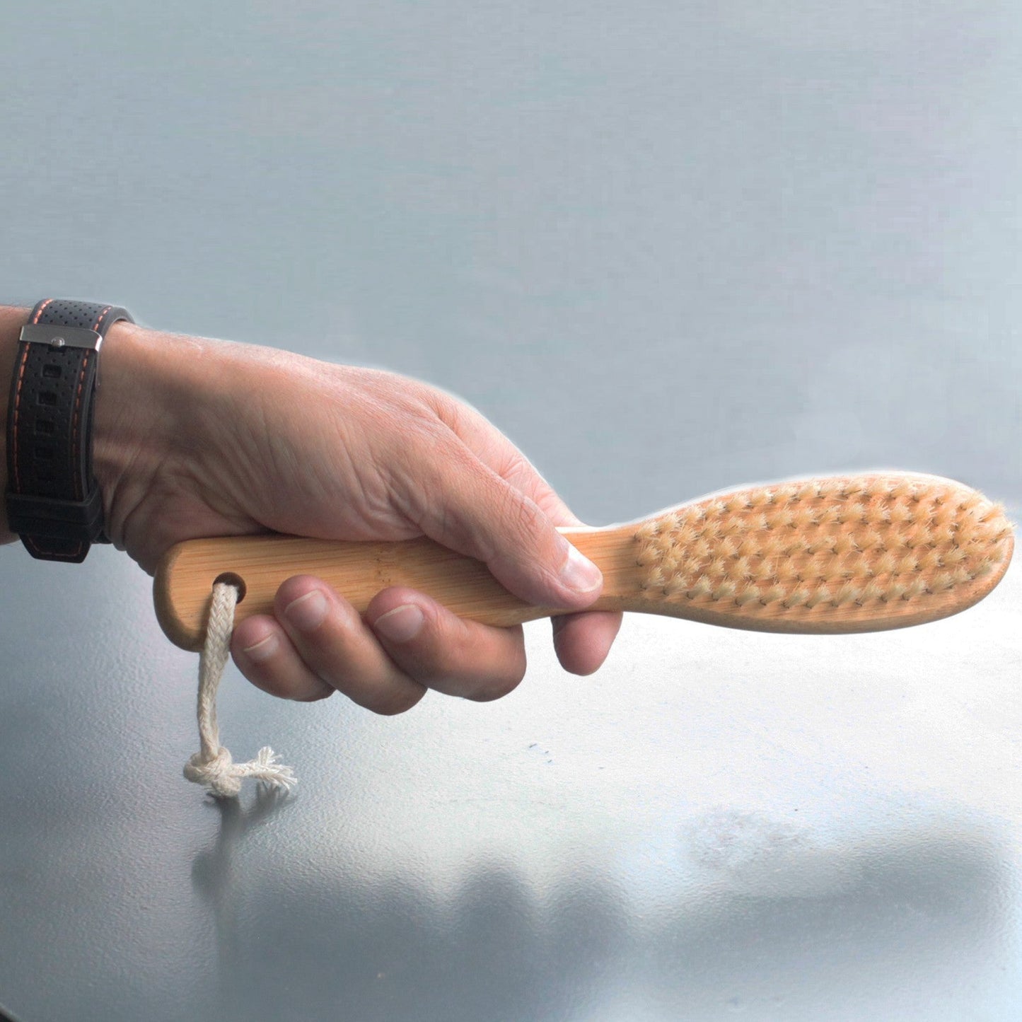 Eco-Friendly Bamboo Beard Brush, held by its handle with the bristles facing upward, by Quintessential Holistic Health Ltd