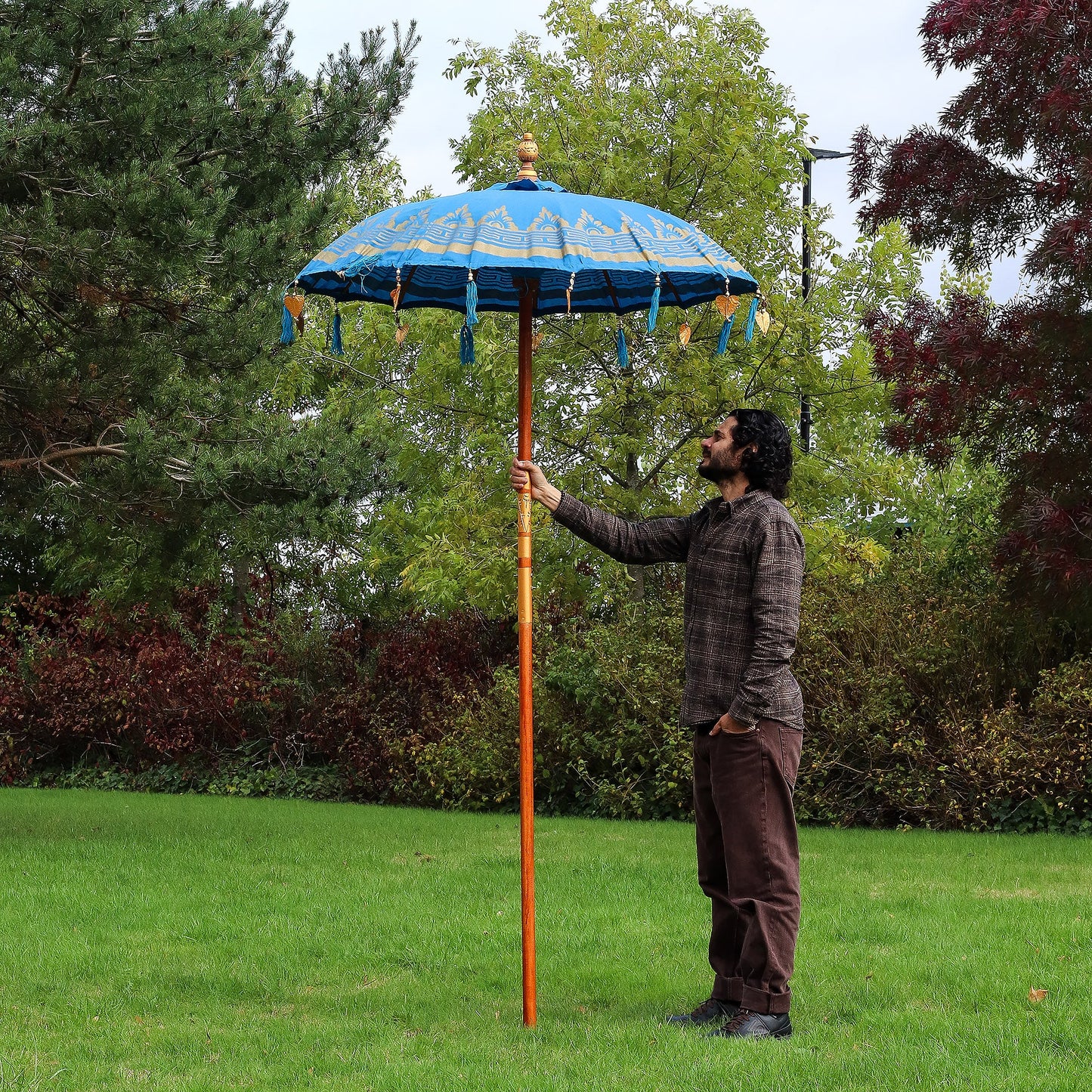 Handcrafted Decorative Parasol - Medium - Turquoise with blue canopy and hanging tassels, held upright on a long orange pole by Quintessential Holistic Health Ltd