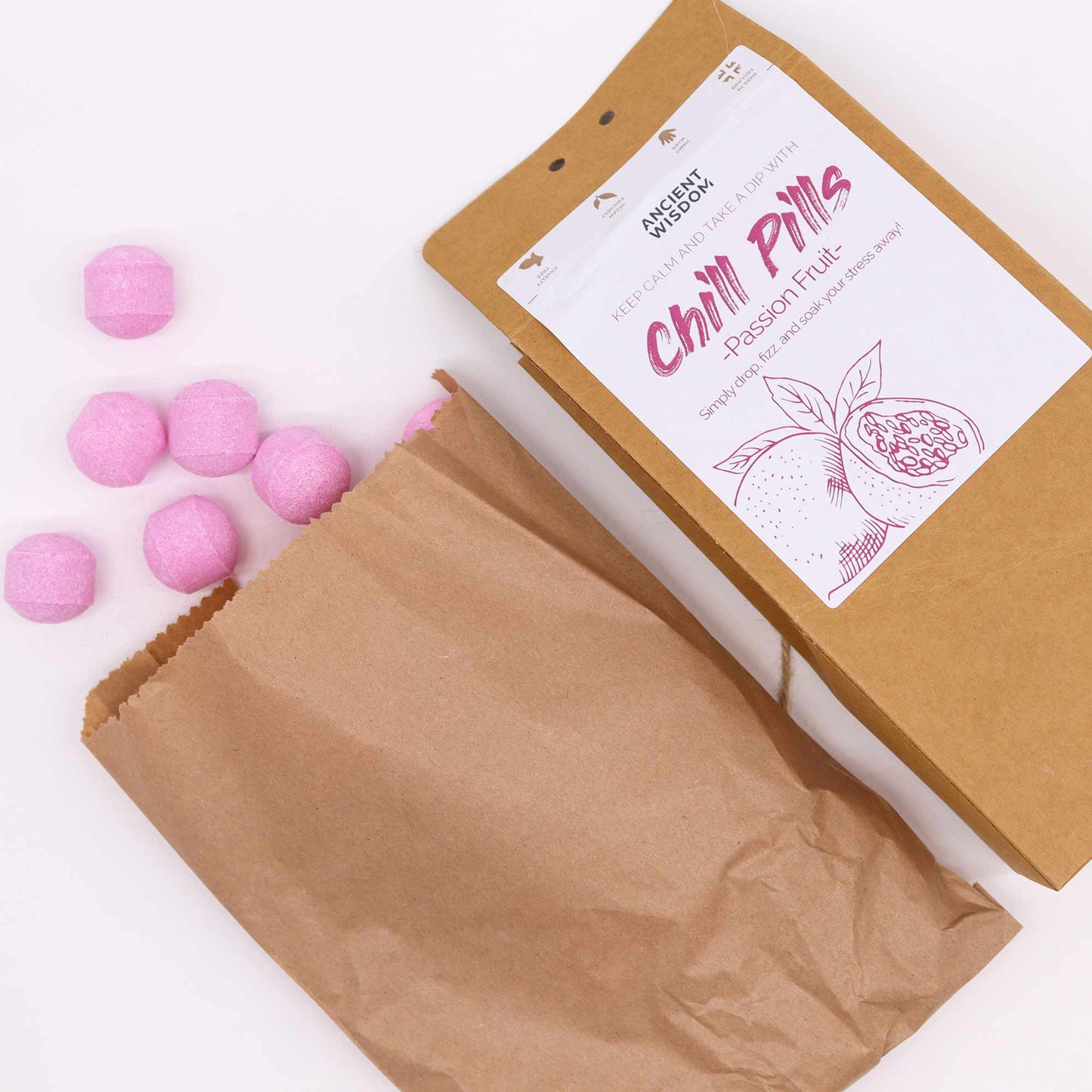 Vegan Bath Bomb Chill Pills Gift Pack - Passion Fruit - 350g, open kraft box beside a paper bag and scattered pink tablets, by Quintessential Holistic Health Ltd