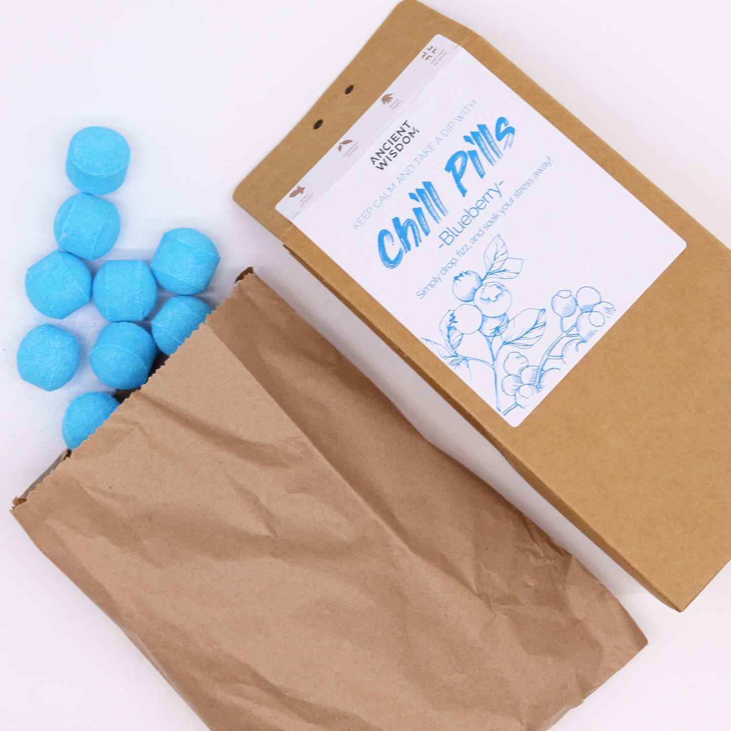 Vegan Bath Bomb Chill Pills Gift Pack - Blueberry - 350g, open kraft box beside a paper bag and scattered bright blue tablets, by Quintessential Holistic Health Ltd
