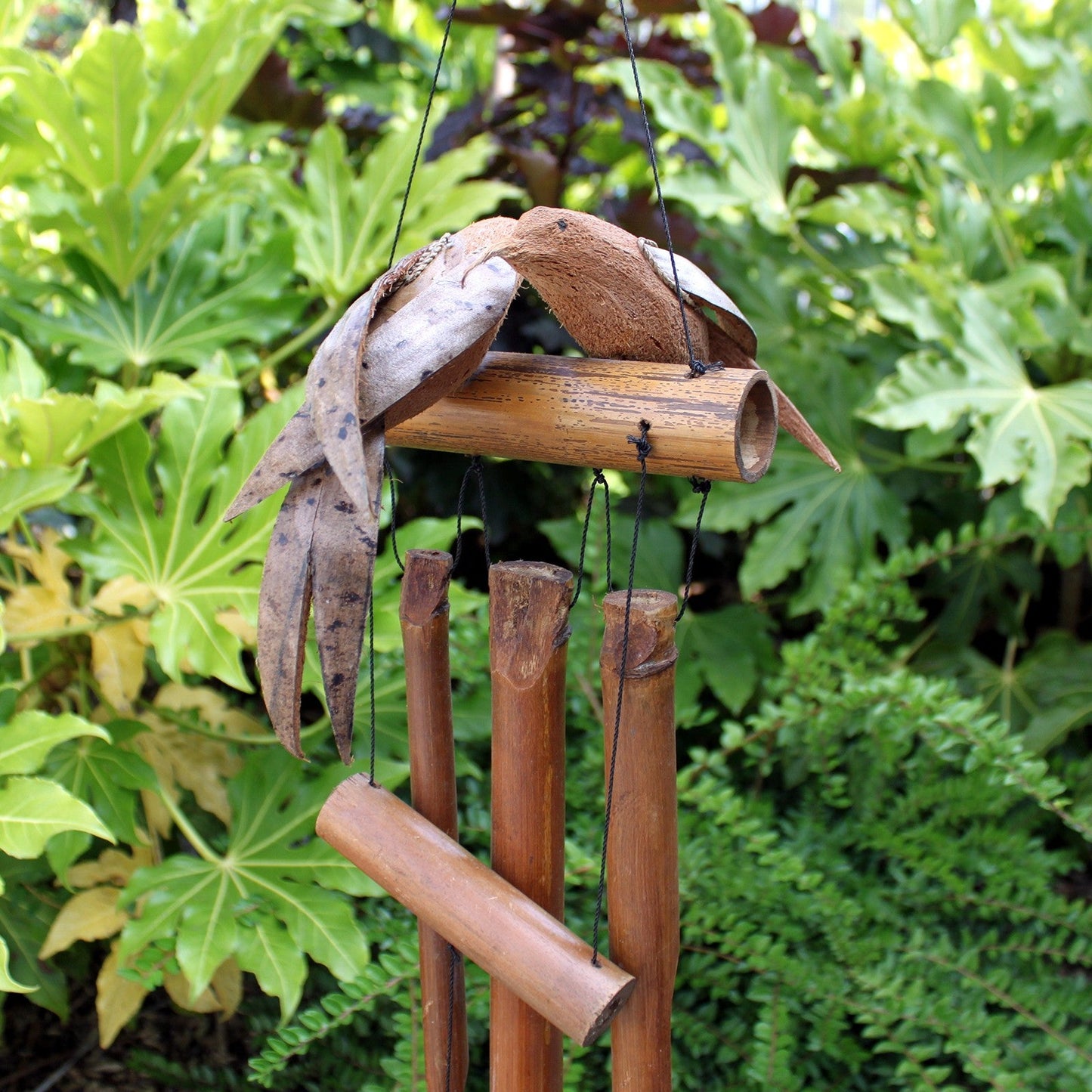 Handcrafted Coconut Shell and Bamboo Wind Chime - Love Birds among green leaves with two birds above brown tubes by Quintessential Holistic Health Ltd