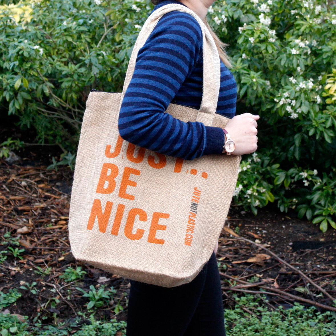 Eco-Friendly Jute Bag - Just Be Nice - Random Black or Yellow with orange lettering carried by a person in a striped top by Quintessential Holistic Health Ltd