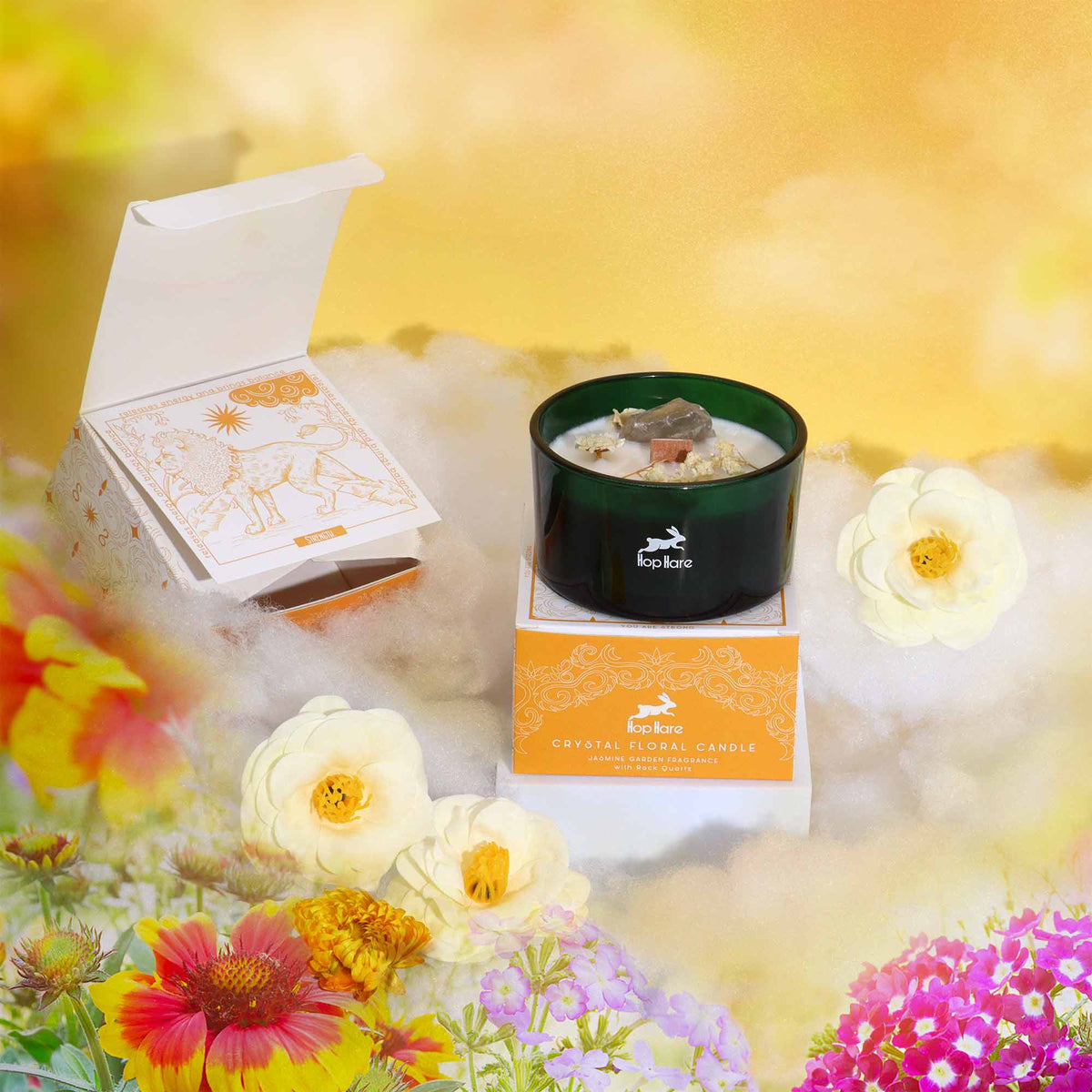 Eco-Friendly Soy Wax Candle - The Lion beside an open orange box and white flowers in a colourful floral setting by Quintessential Holistic Health Ltd