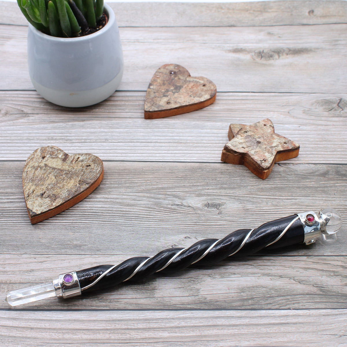 Handmade Twisted Teak Healing Wand - Silver Rock Quartz lying diagonally beside wooden heart and star ornaments by Quintessential Holistic Health Ltd