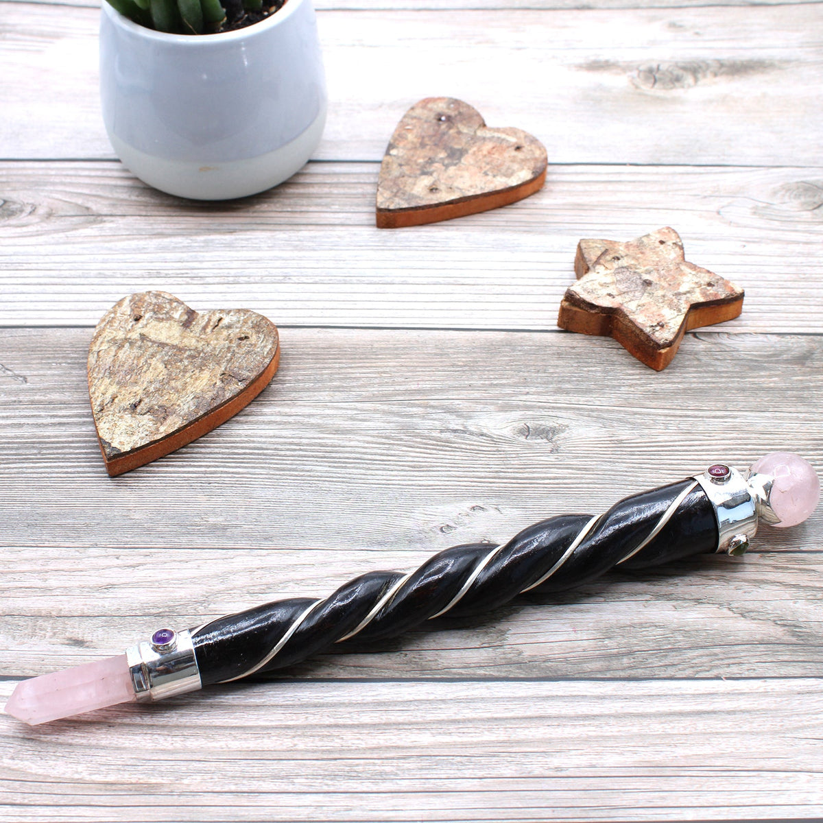 Handmade Twisted Teak Healing Wand - Silver Rose Quartz lying diagonally beside wooden heart and star ornaments by Quintessential Holistic Health Ltd