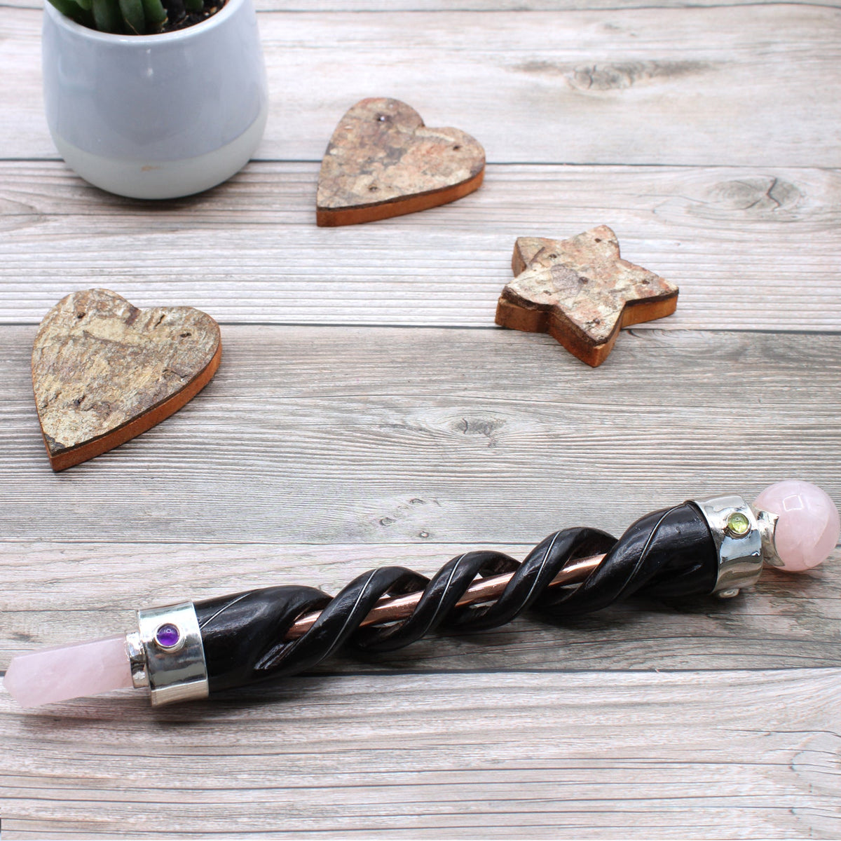 Spiral Teak Wood Healing Wand with Copper - Rose Quartz with dark spiral shaft and pale pink ends on a pale wooden surface by Quintessential Holistic Health Ltd