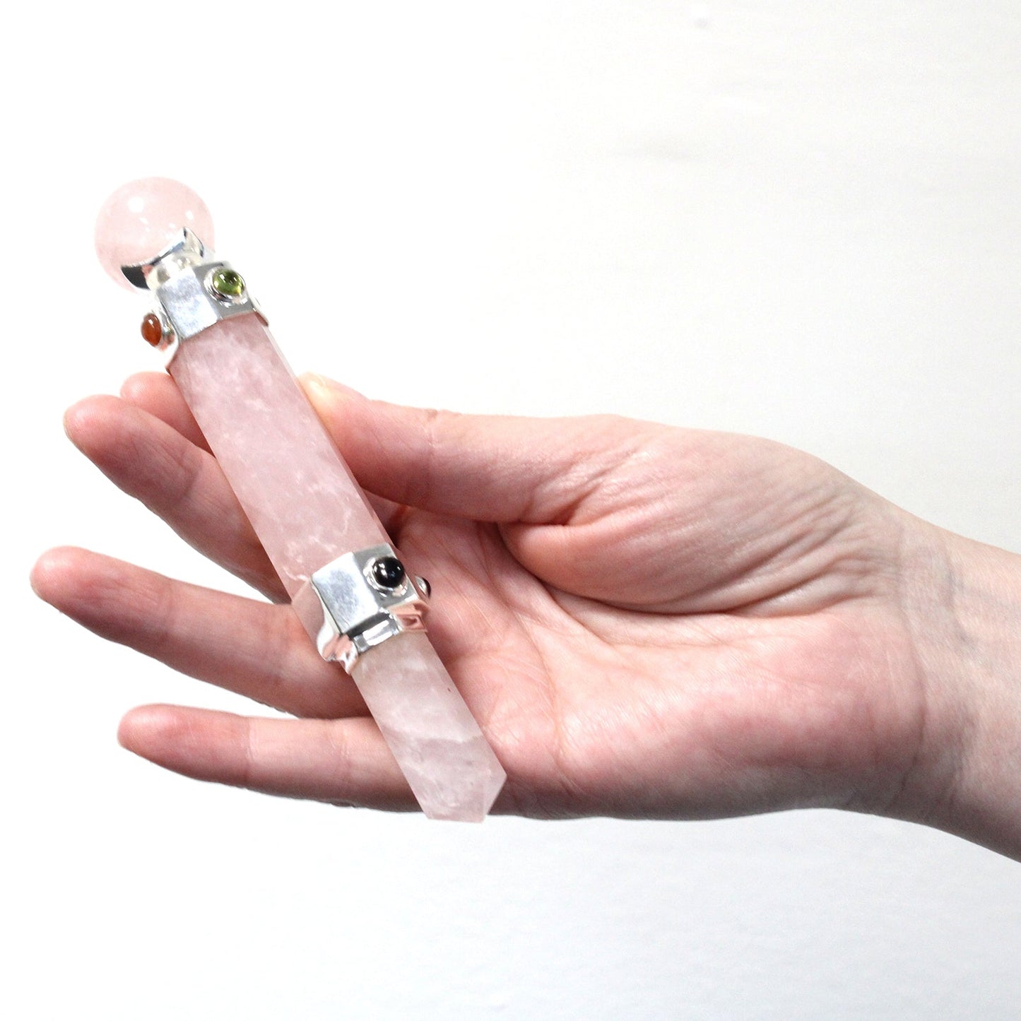 Handmade Hexagonal Healing Wand - Rock Quartz Gemstone held in a hand, with pale pink shaft and round end by Quintessential Holistic Health Ltd