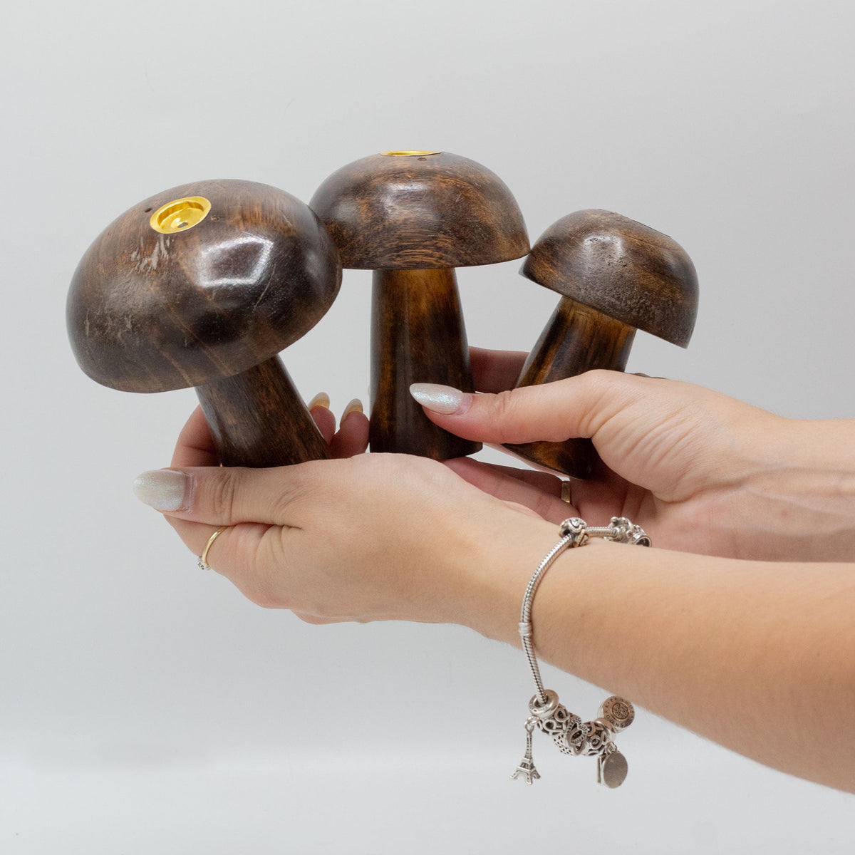 Set of 3 Mango Wood Incense Holders - Button Mushrooms, three rounded dark brown pieces held together in two hands by Quintessential Holistic Health Ltd