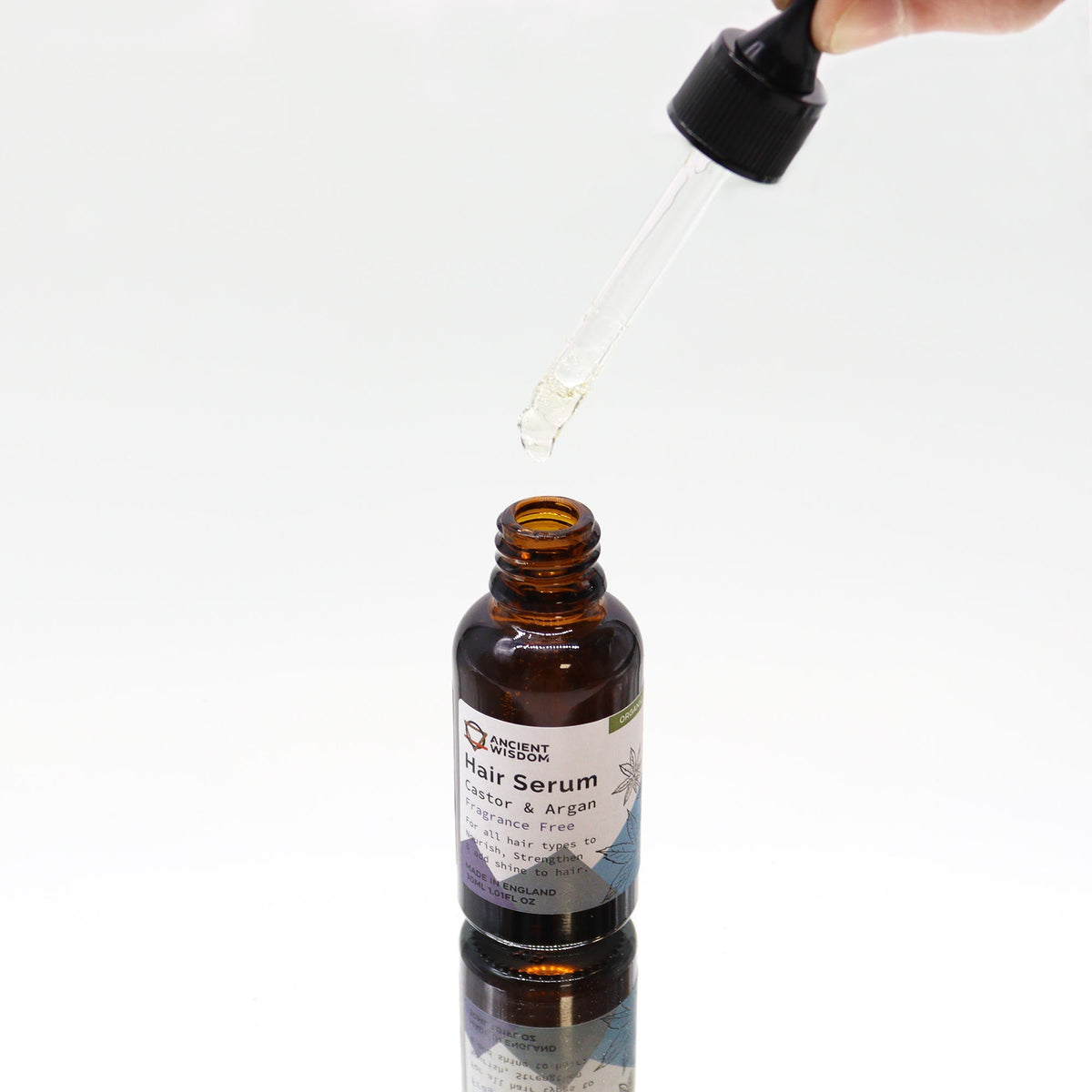 Organic Vegan-Friendly Unfragranced Hair Serum - 30ml, open amber bottle below a glass dropper held from above, by Quintessential Holistic Health Ltd