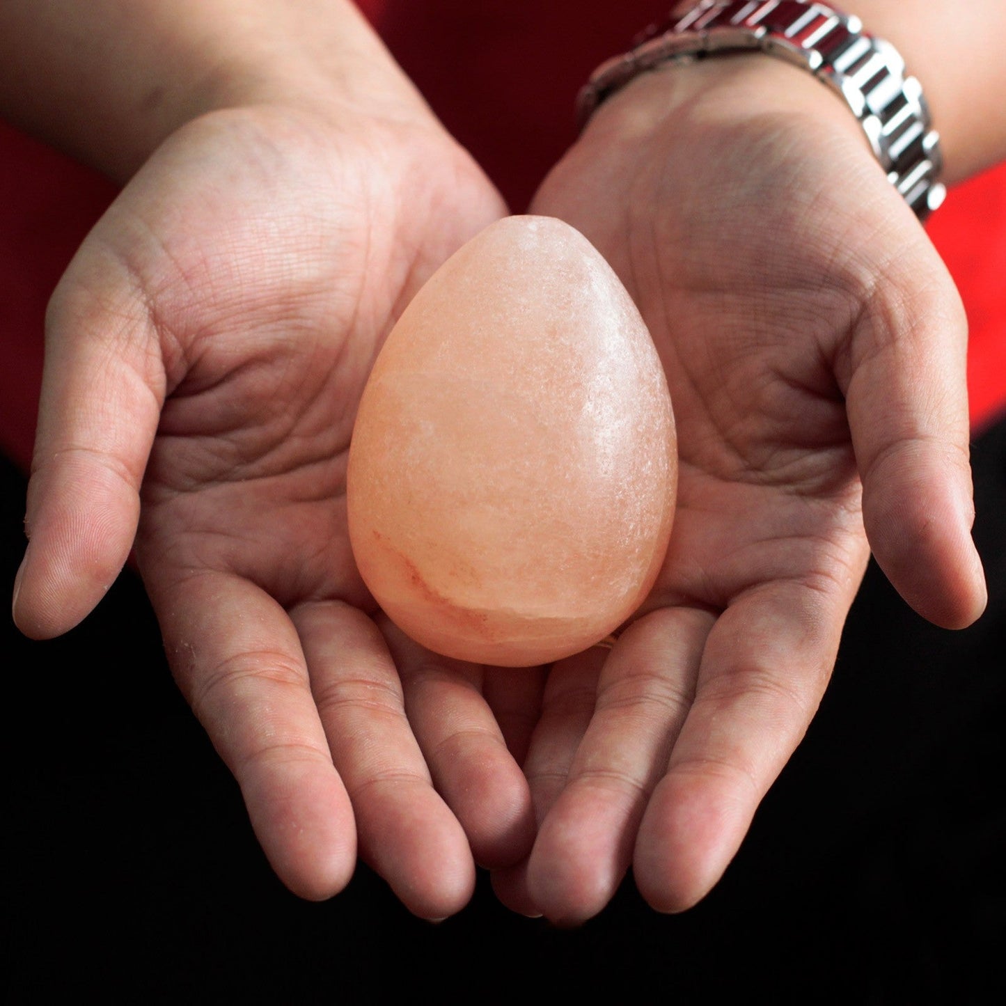 Himalayan Salt Deodorant & Massage Stone - Egg - 1 Pack, pale orange egg-shaped stone resting in two hands, by Quintessential Holistic Health Ltd