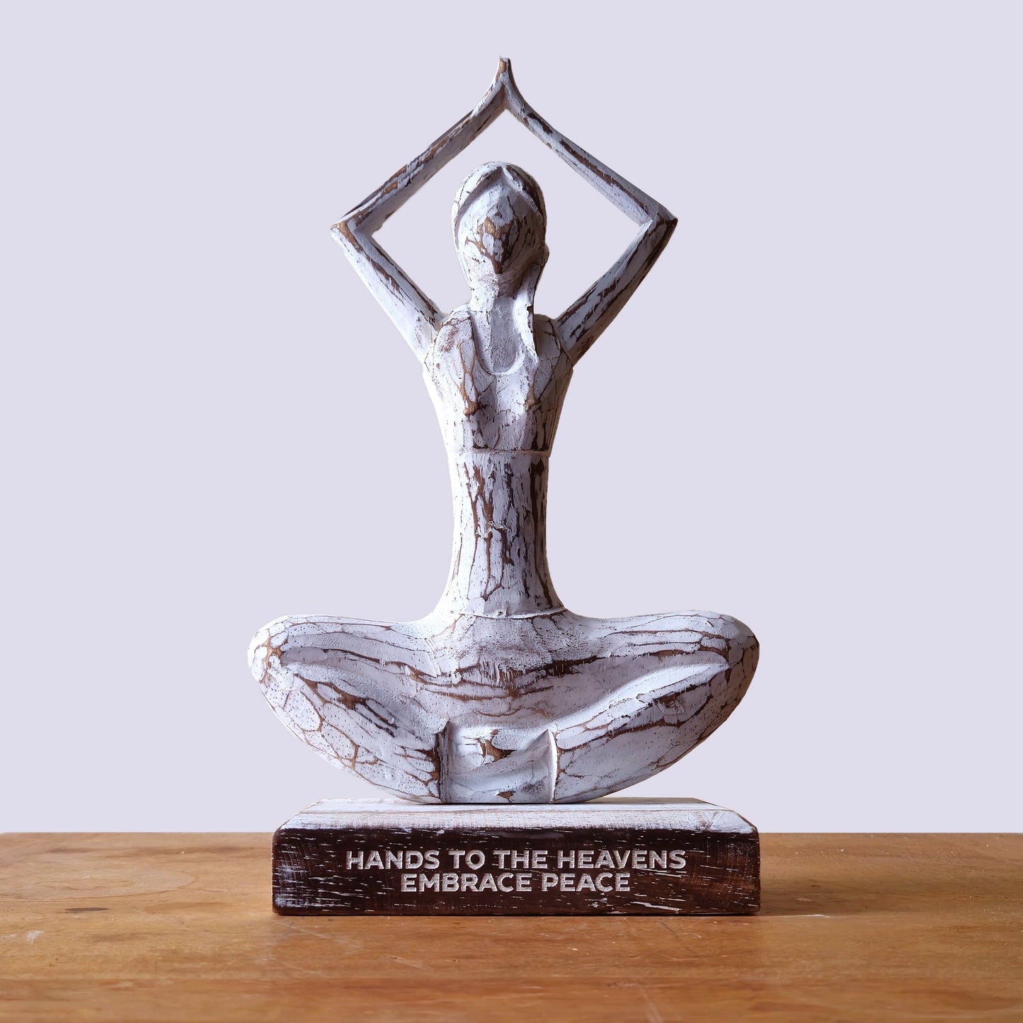Albasia Wood Yoga Lady - Hands Up Pose - Embrace Peace - Whitewash displayed on a wooden surface against a pale lilac background by Quintessential Holistic Health Ltd