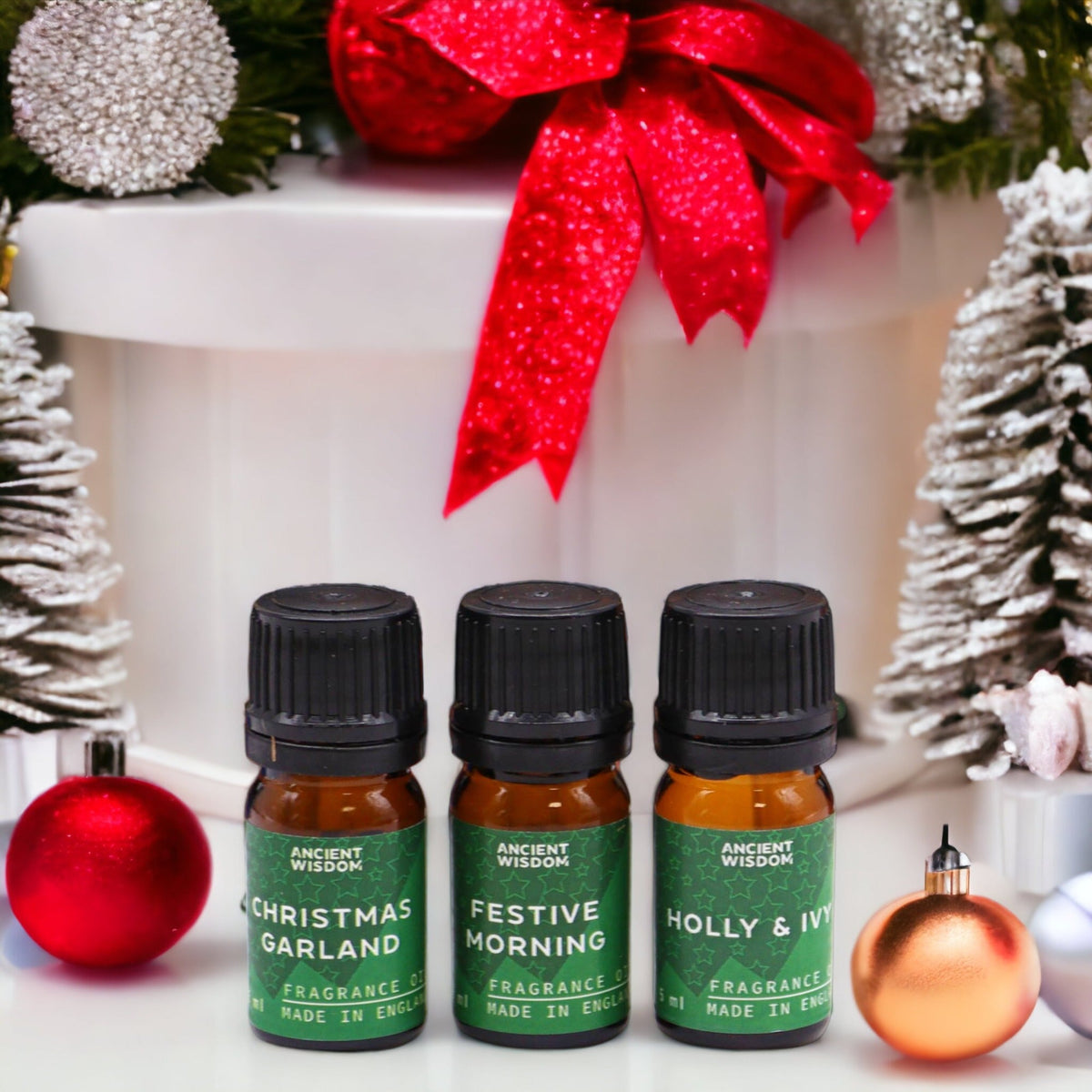 Holy Scent Christmas Fragrance Oil Set - 5 ml Bottles with three green-labelled bottles among red, silver and gold decorations by Quintessential Holistic Health Ltd