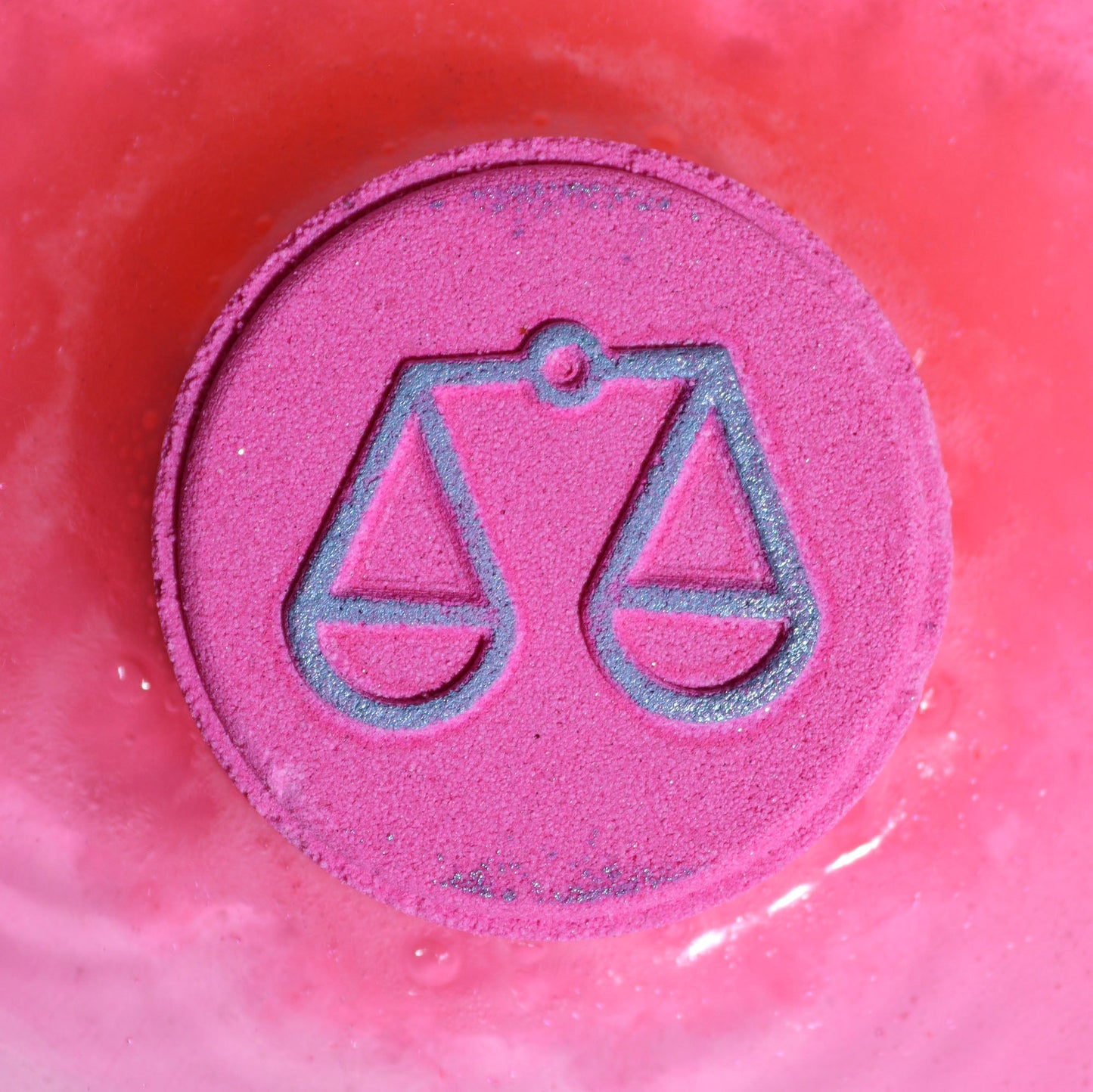 Libra Zodiac Bath Bomb Fizzers - Cool Jade & Oak Moss - 2 Pack, close-up of a bright pink fizzer embossed with scales by Quintessential Holistic Health Ltd