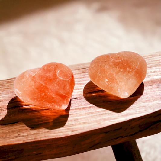 2 Heart Shaped Himalayan Mineral Salt Deodorant Massage Stones Placed on a Stool