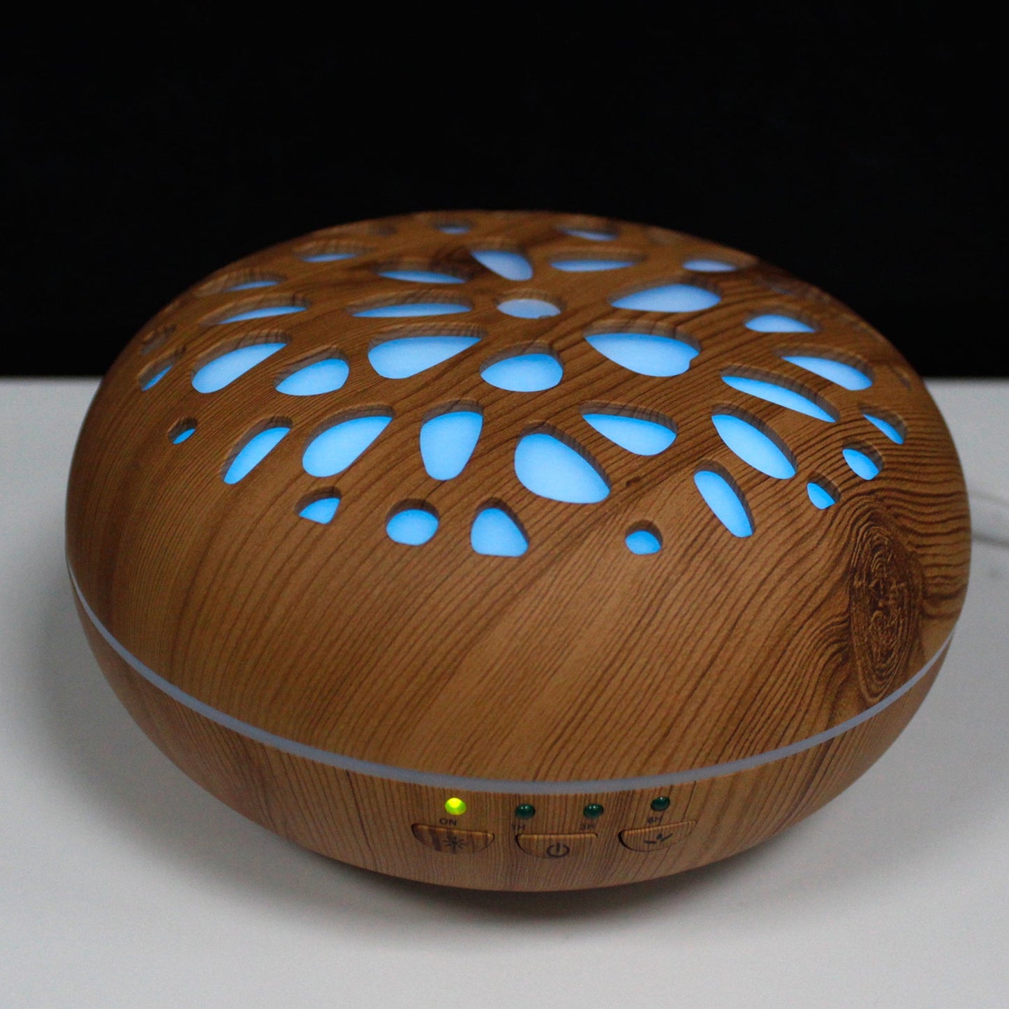 Colour-Changing USB Aroma Diffuser - Oslo Pebble with a wood-effect oval body glowing blue through leaf-shaped cutouts by Quintessential Holistic Health Ltd