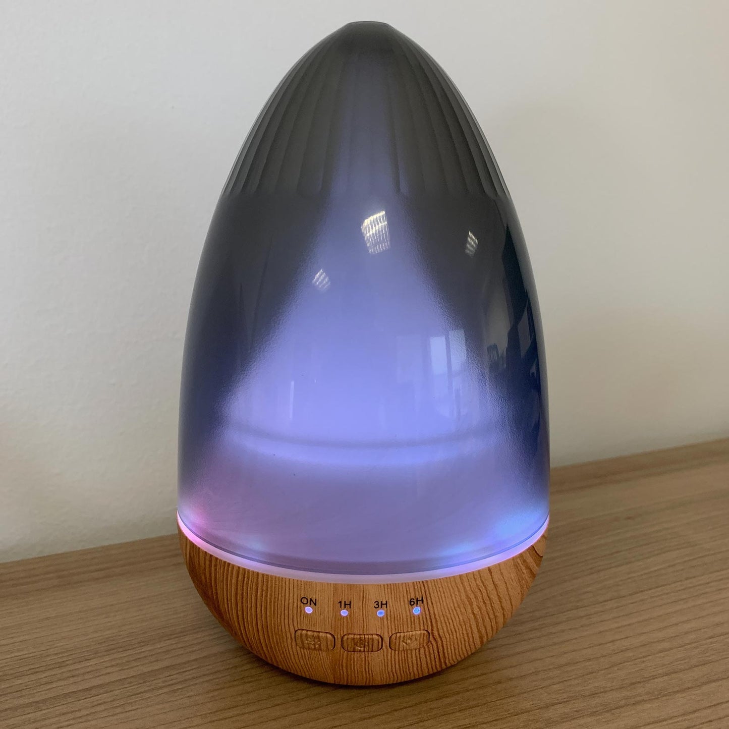 Colour-Changing USB Aroma Diffuser - Barcelona, dark teardrop-shaped diffuser glowing blue and purple above a wood-effect base by Quintessential Holistic Health Ltd
