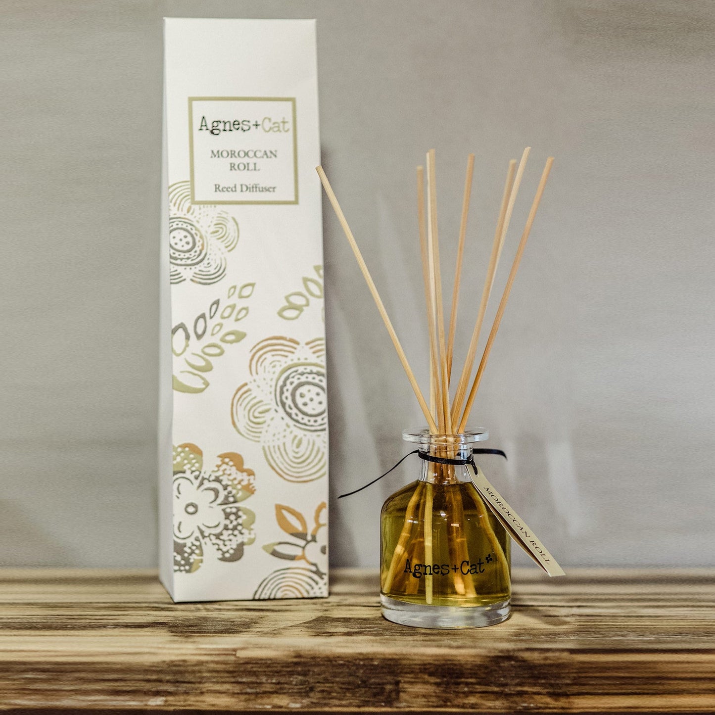 Reed Diffuser - Moroccan Roll - 140ml, golden-brown bottle with natural-coloured reeds beside a tall illustrated box by Quintessential Holistic Health Ltd