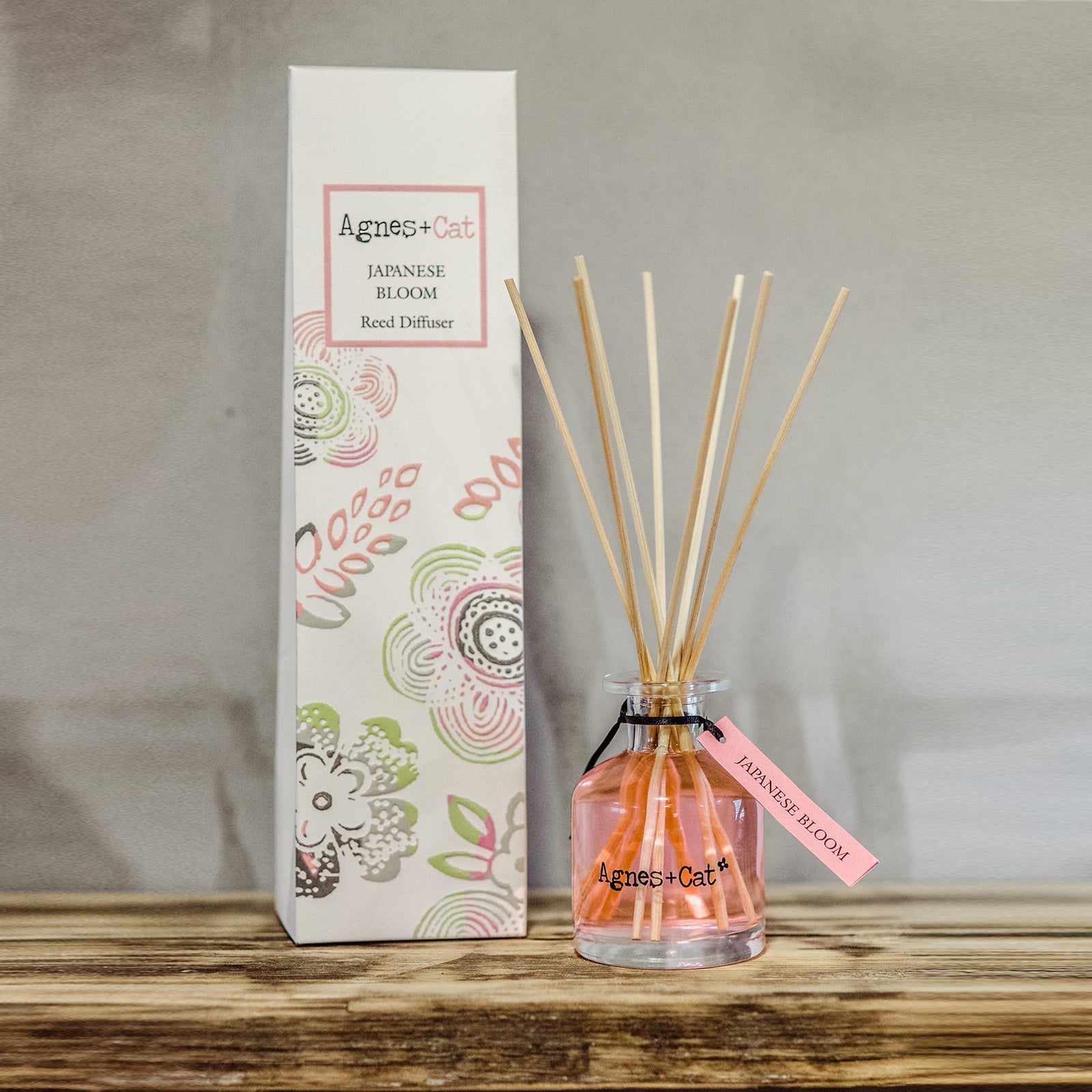 Reed Diffuser - Japanese Bloom - 140ml, pink bottle with natural-coloured reeds beside a tall pink-accented illustrated box by Quintessential Holistic Health Ltd
