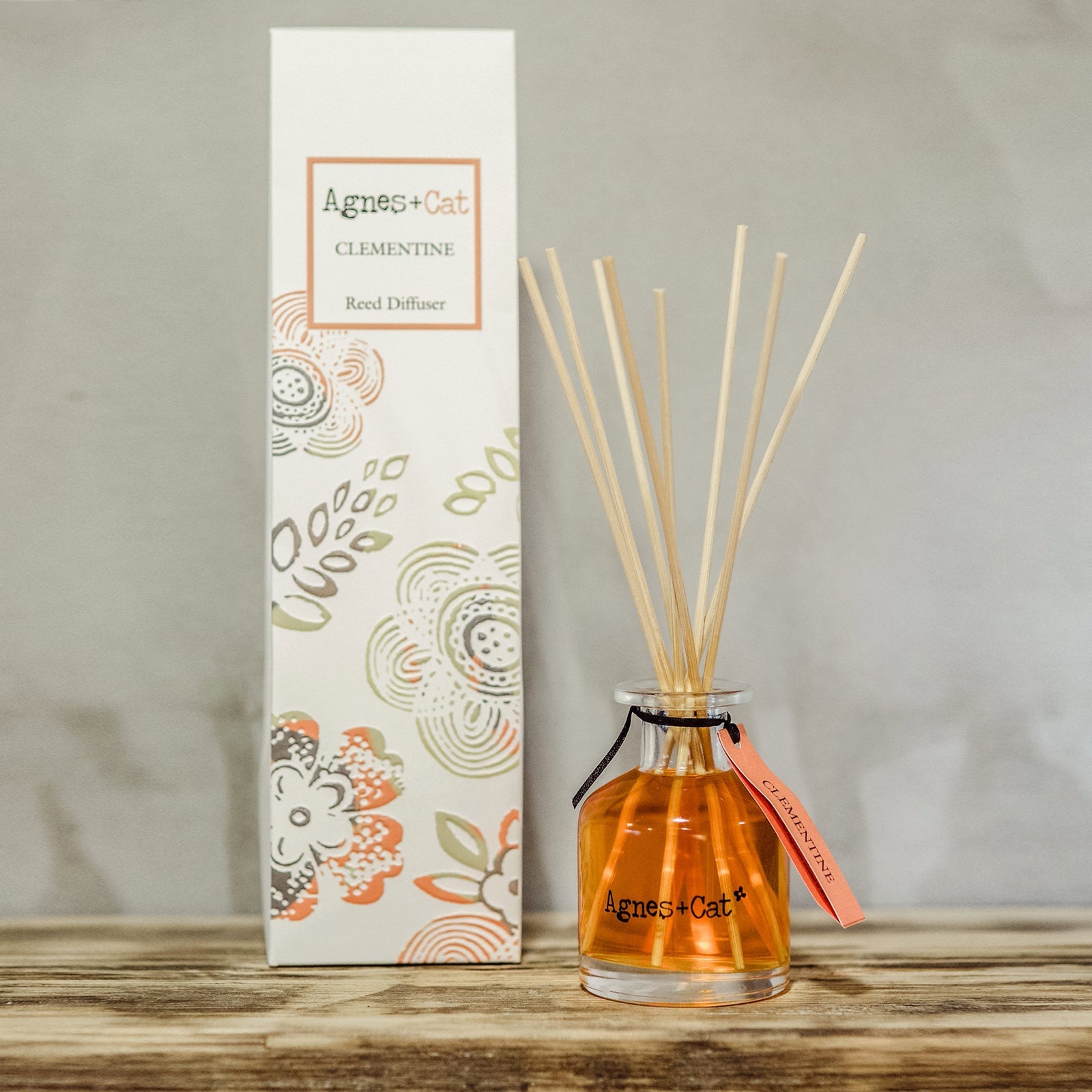 Reed Diffuser - Clementine - 140ml, amber bottle and reeds beside a tall patterned box on a wooden surface by Quintessential Holistic Health Ltd