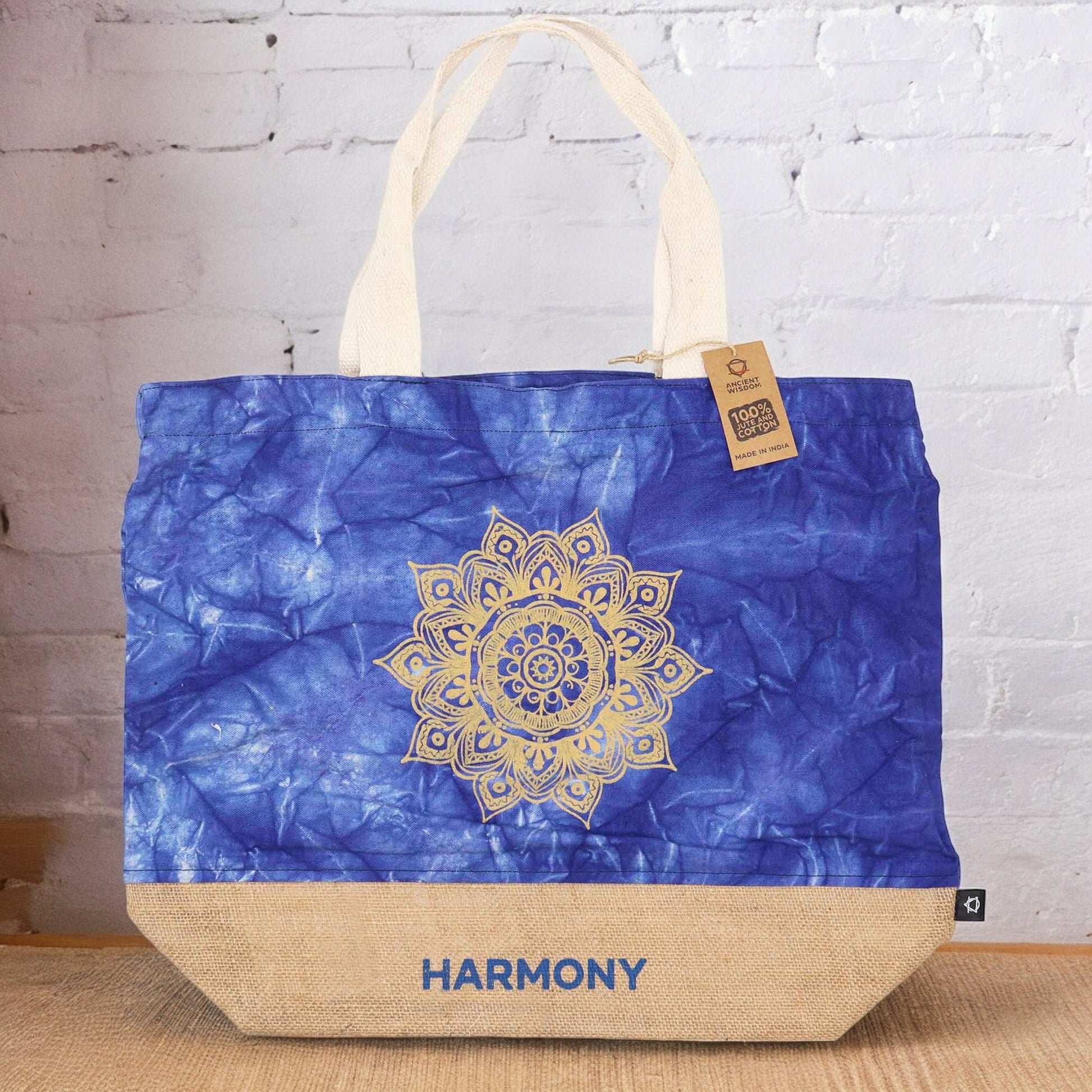 Blue Stonewash Jute & Cotton Tote Bag - Mandala - Harmony standing against a white brick wall with its gold mandala design visible by Quintessential Holistic Health Ltd