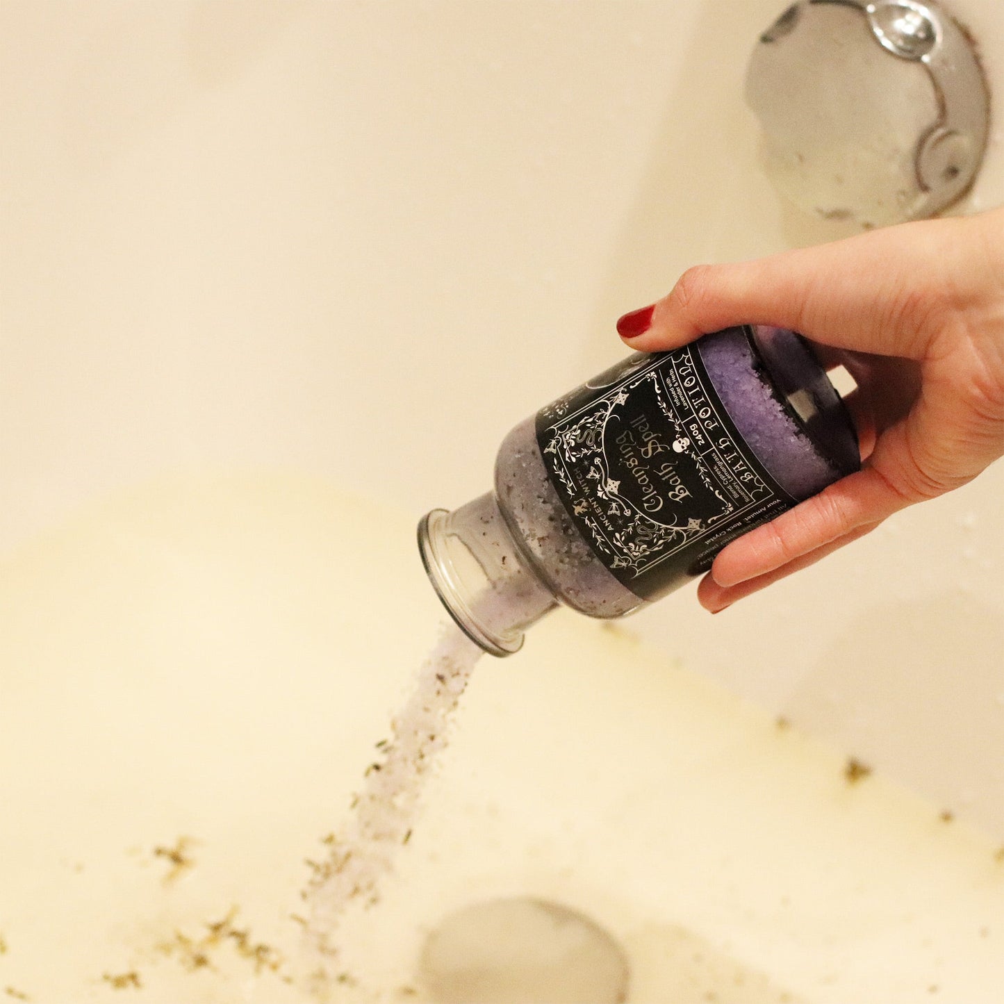 Vegan Bath Spell Potion & Rock Crystal Amulet - Cleansing, tipped over a white bath as pale grains pour from the bottle by Quintessential Holistic Health Ltd