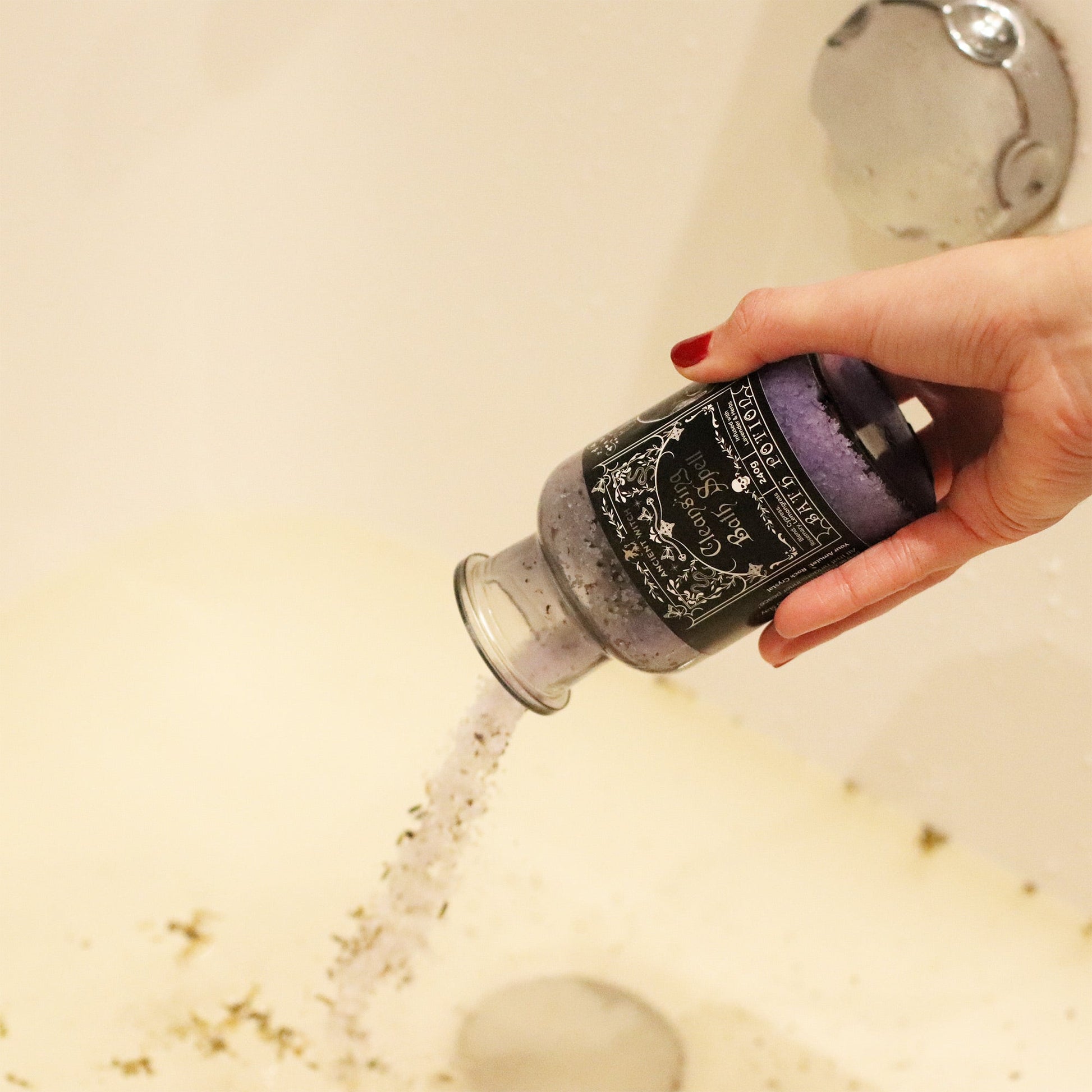 Vegan Bath Spell Potion & Rock Crystal Amulet - Cleansing, tipped over a white bath as pale grains pour from the bottle by Quintessential Holistic Health Ltd