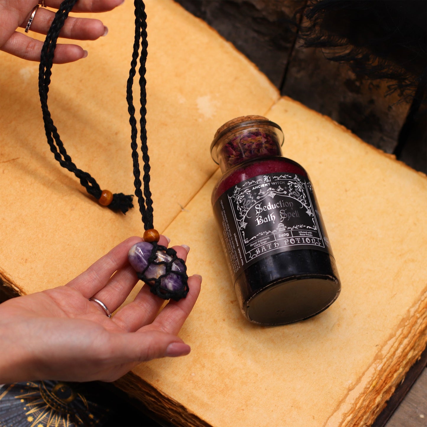 Vegan Bath Spell Potion & Rock Crystal Amulet - Cleansing, beside a hand holding the crystal amulet on its black cord by Quintessential Holistic Health Ltd