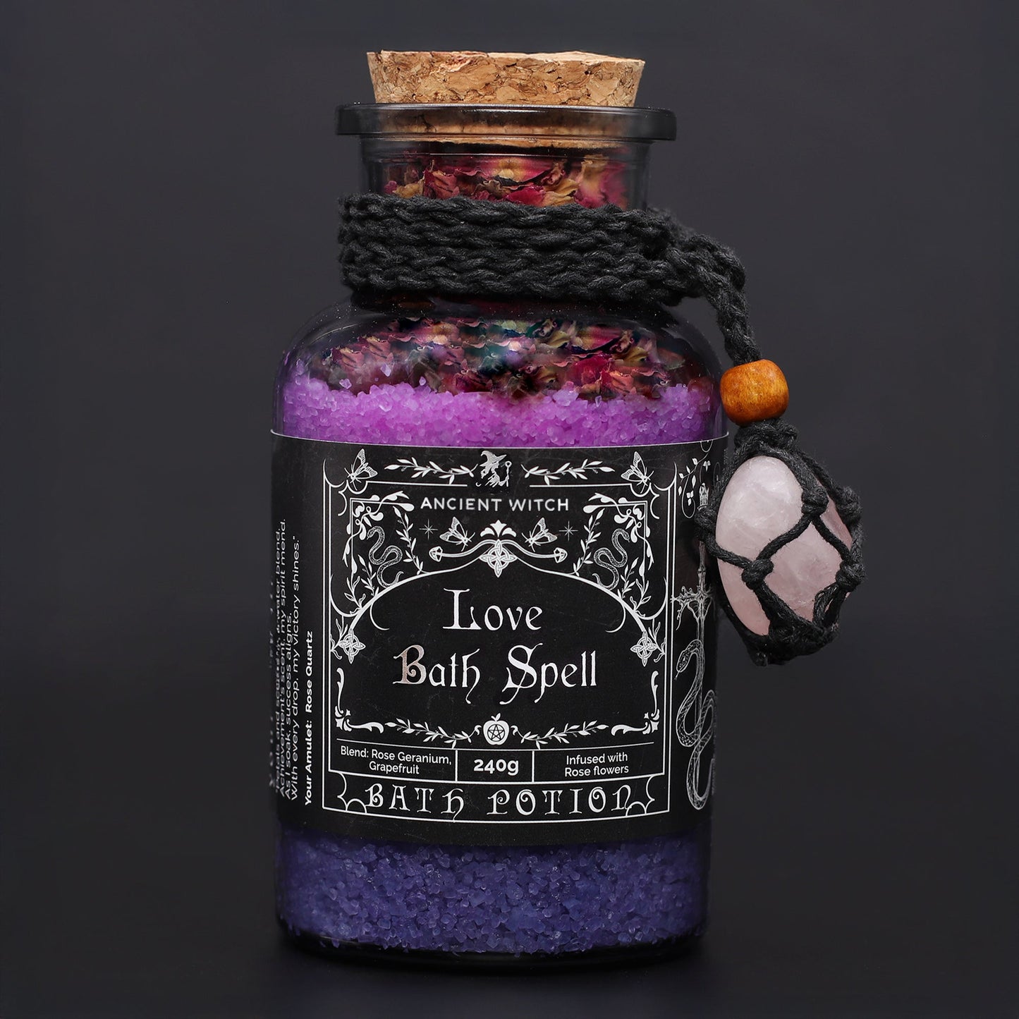 Vegan Bath Spell Potion & Rose Quartz Crystal Amulet - Love, corked purple bottle with black cord and pink charm on a dark background by Quintessential Holistic Health Ltd