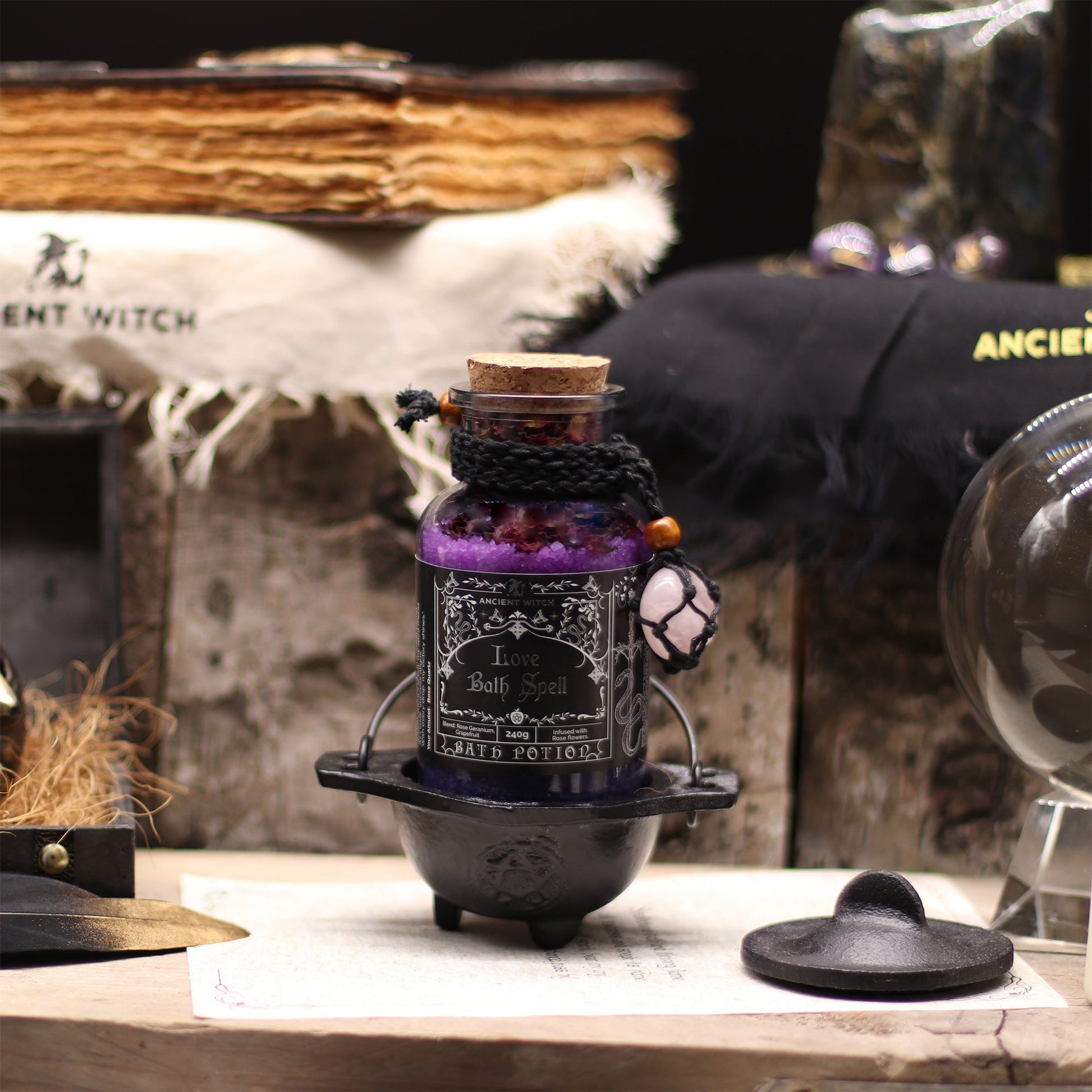 Vegan Bath Spell Potion & Rose Quartz Crystal Amulet - Love, corked purple bottle displayed in a small black cauldron by Quintessential Holistic Health Ltd