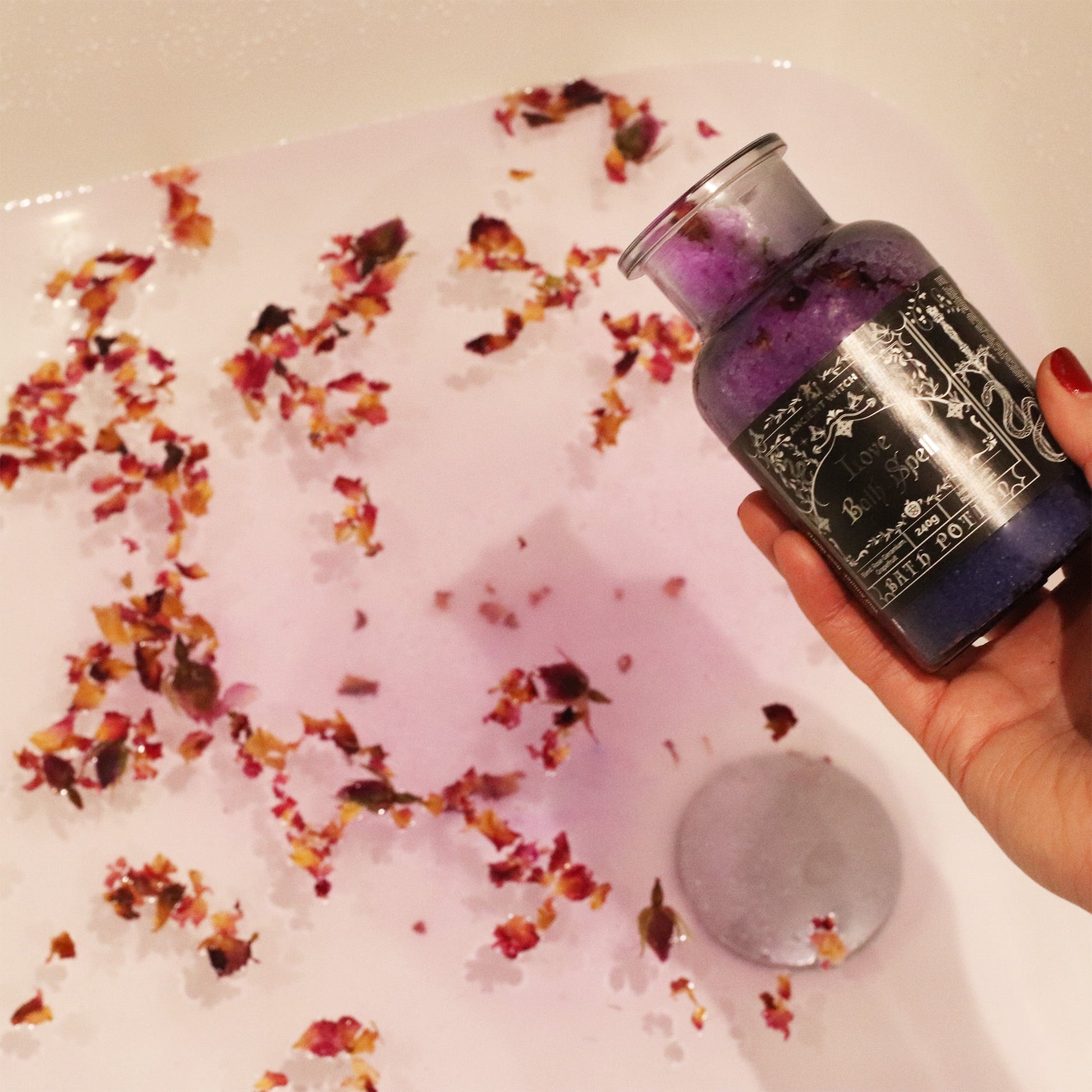 Vegan Bath Spell Potion & Rose Quartz Crystal Amulet - Love, held above pink bathwater scattered with rose petals by Quintessential Holistic Health Ltd