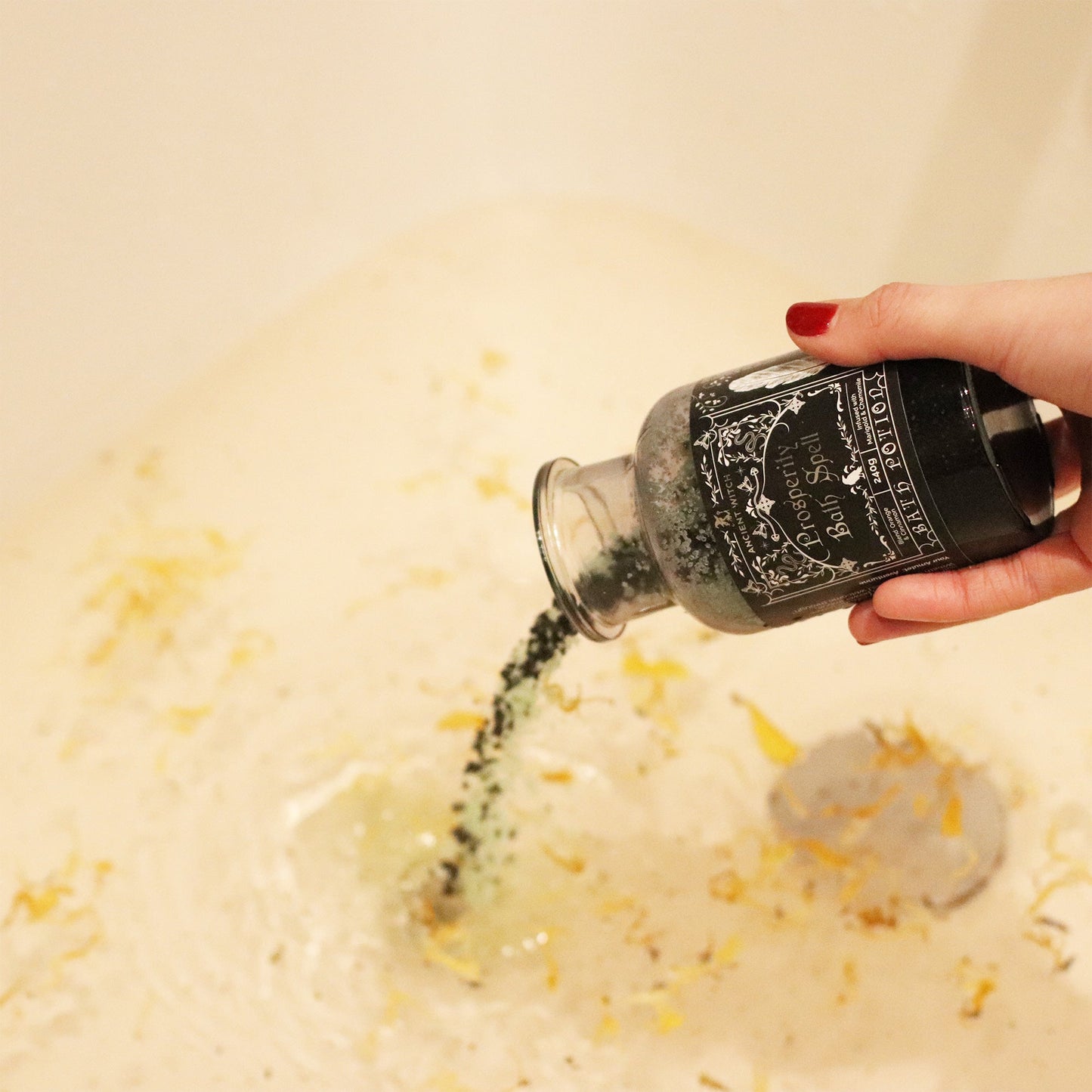 Vegan Bath Spell Potion & Aventurine Crystal Amulet - Prosperity, tipped by a hand as green grains fall into pale bathwater, by Quintessential Holistic Health Ltd