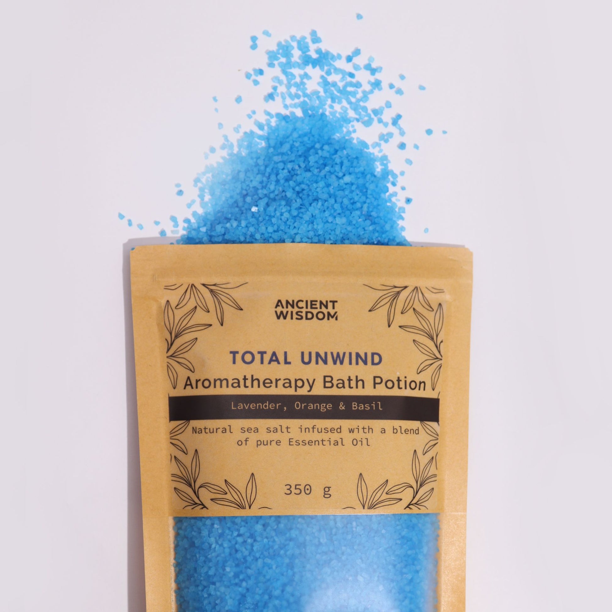 Aromatherapy Bath Potion - Kraft Bag - Total Unwind - 350g with blue granules spraying above the labelled kraft pouch by Quintessential Holistic Health Ltd
