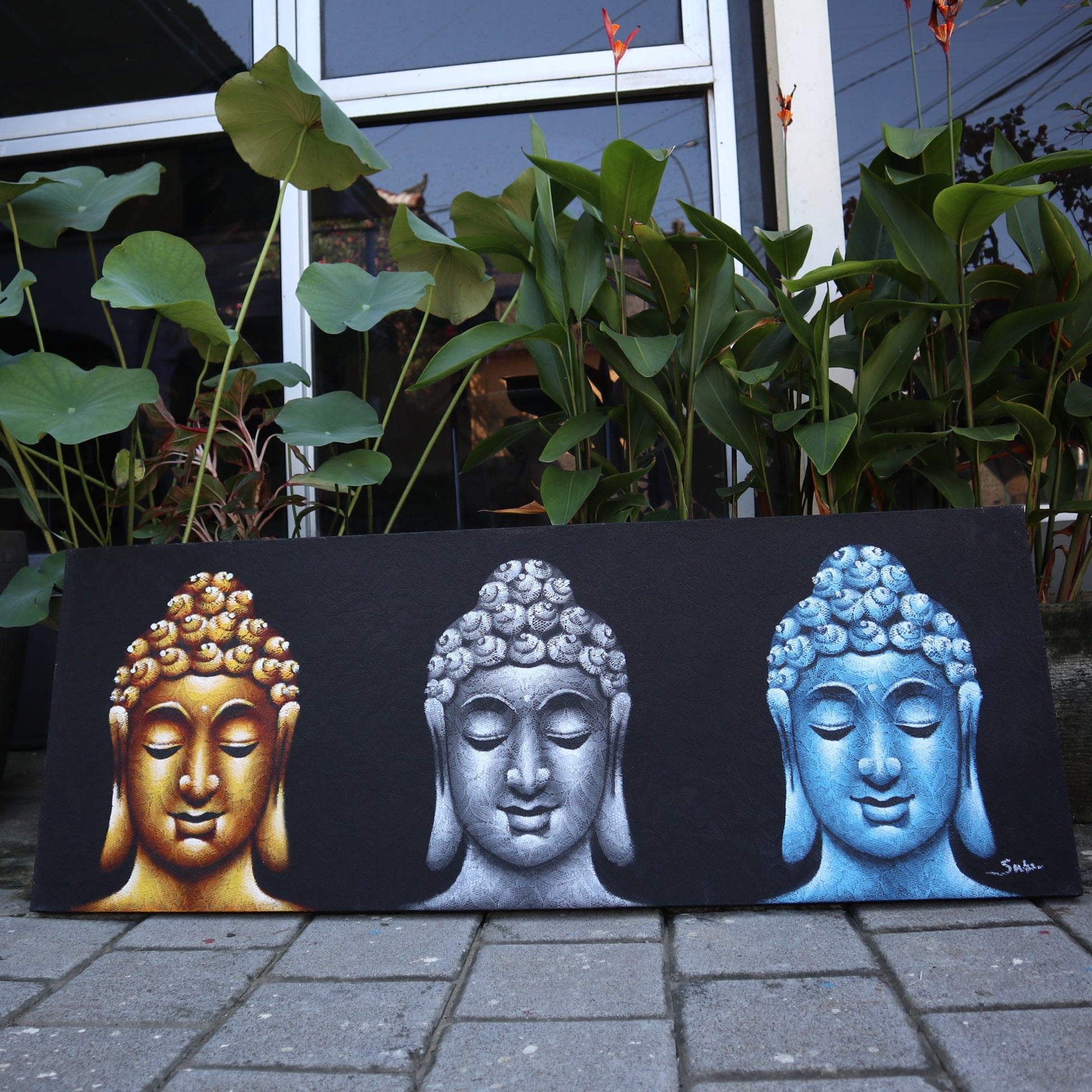 Hand Painted Buddha Painting - Black - Three Heads, gold, silver and blue Buddha heads displayed outdoors by Quintessential Holistic Health Ltd