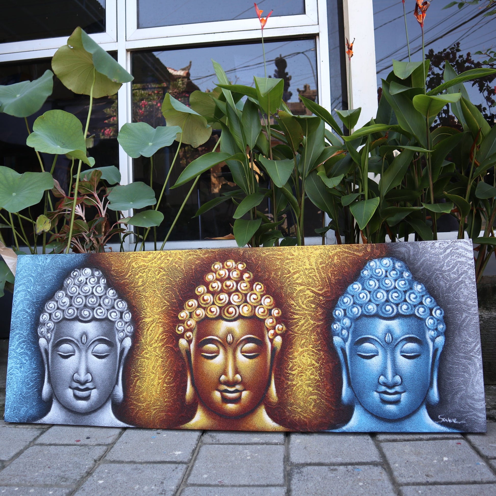 Hand-Painted Buddha Painting - Gold Detail - Three Head, silver, gold and blue Buddha heads displayed outdoors by Quintessential Holistic Health Ltd