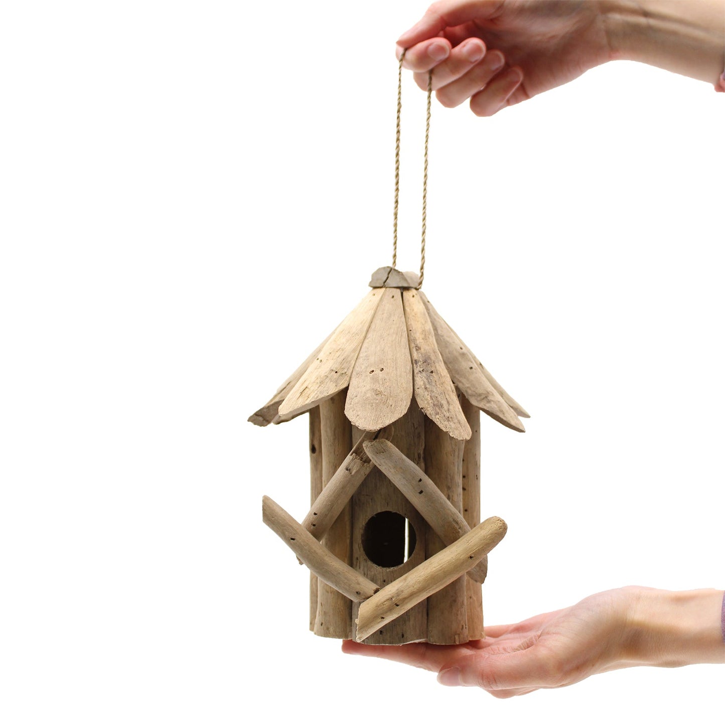 Handmade Recycled Driftwood Bird Box - Medium suspended by a cord above a hand, with a round entrance and crossed front branches by Quintessential Holistic Health Ltd