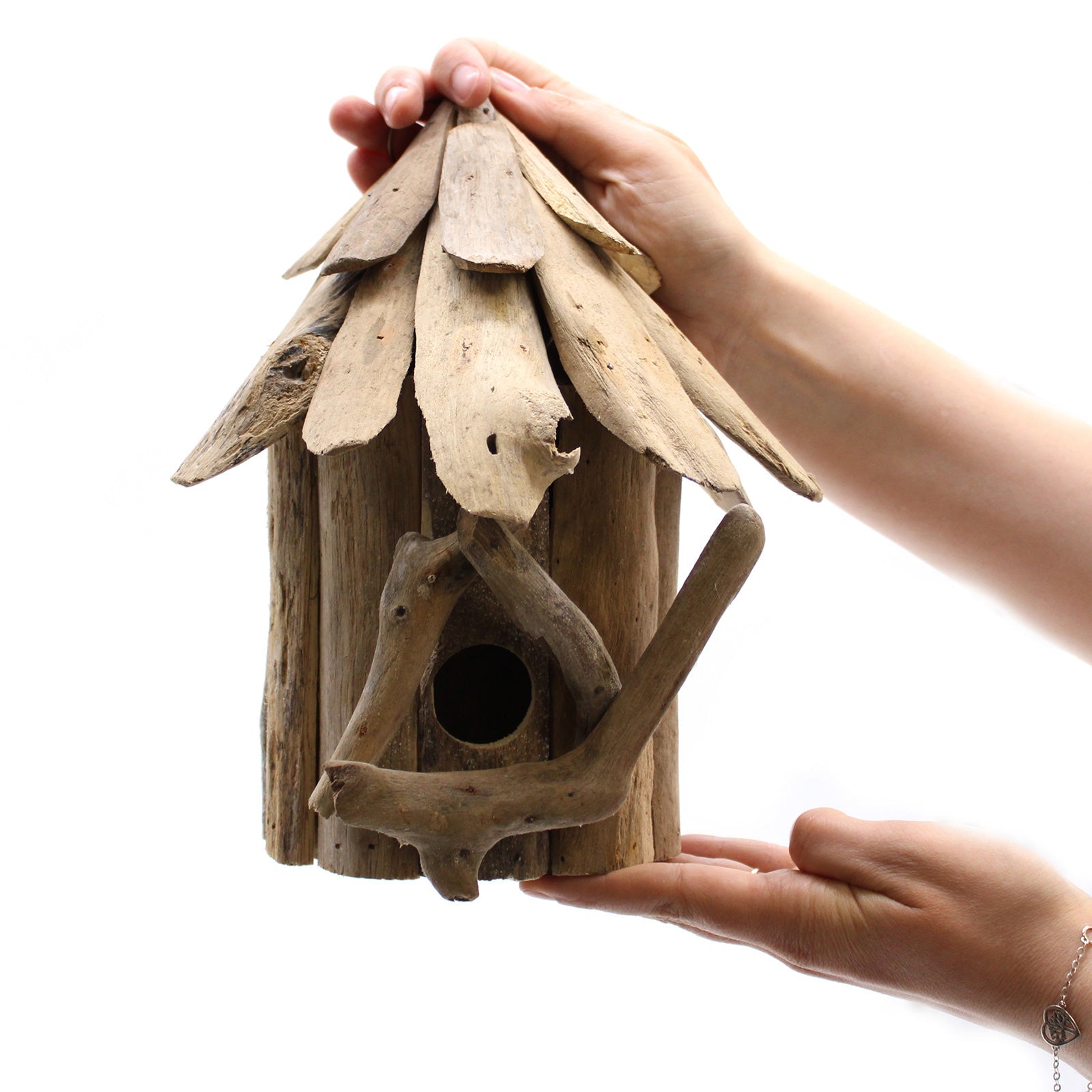 Handmade Wall-Hanging Recycled Driftwood Bird Box with a round entrance and layered pitched roof, held between two hands by Quintessential Holistic Health Ltd