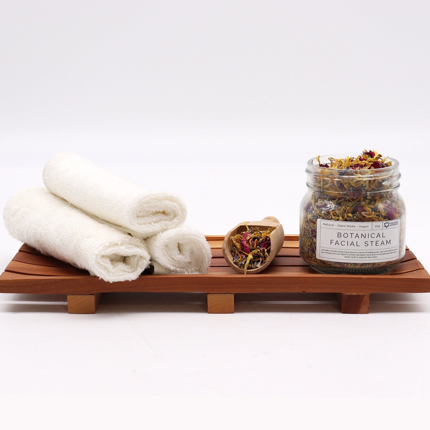Natural Floral Bath Soak - 140g, labelled jar beside rolled white towels and a small bowl of dried petals on a wooden tray, by Quintessential Holistic Health Ltd