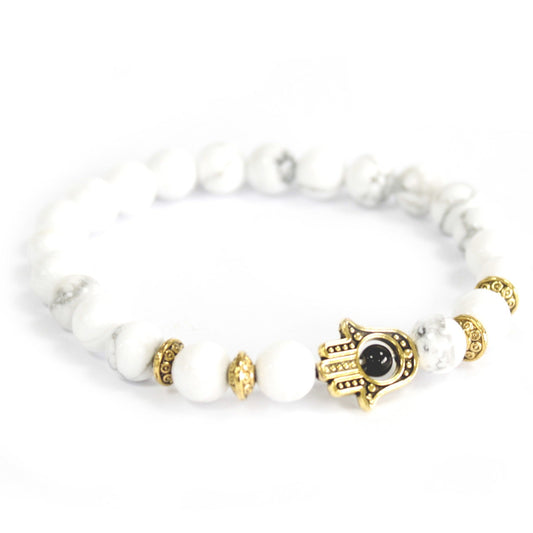 Unisex Handcrafted Boho Gemstone Bracelet - White Howlite Gemstones / Gold Hamsa product packaging on clean background from Quintessential Holistic Health Ltd
