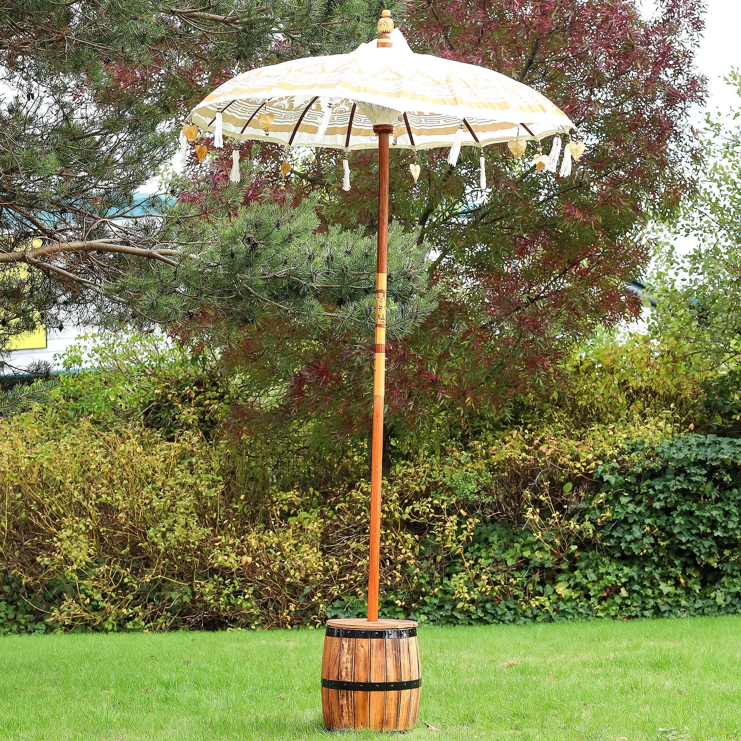 Handcrafted Decorative Parasol - Medium - Natural, standing open outdoors with gold trim and dangling ornaments by Quintessential Holistic Health Ltd