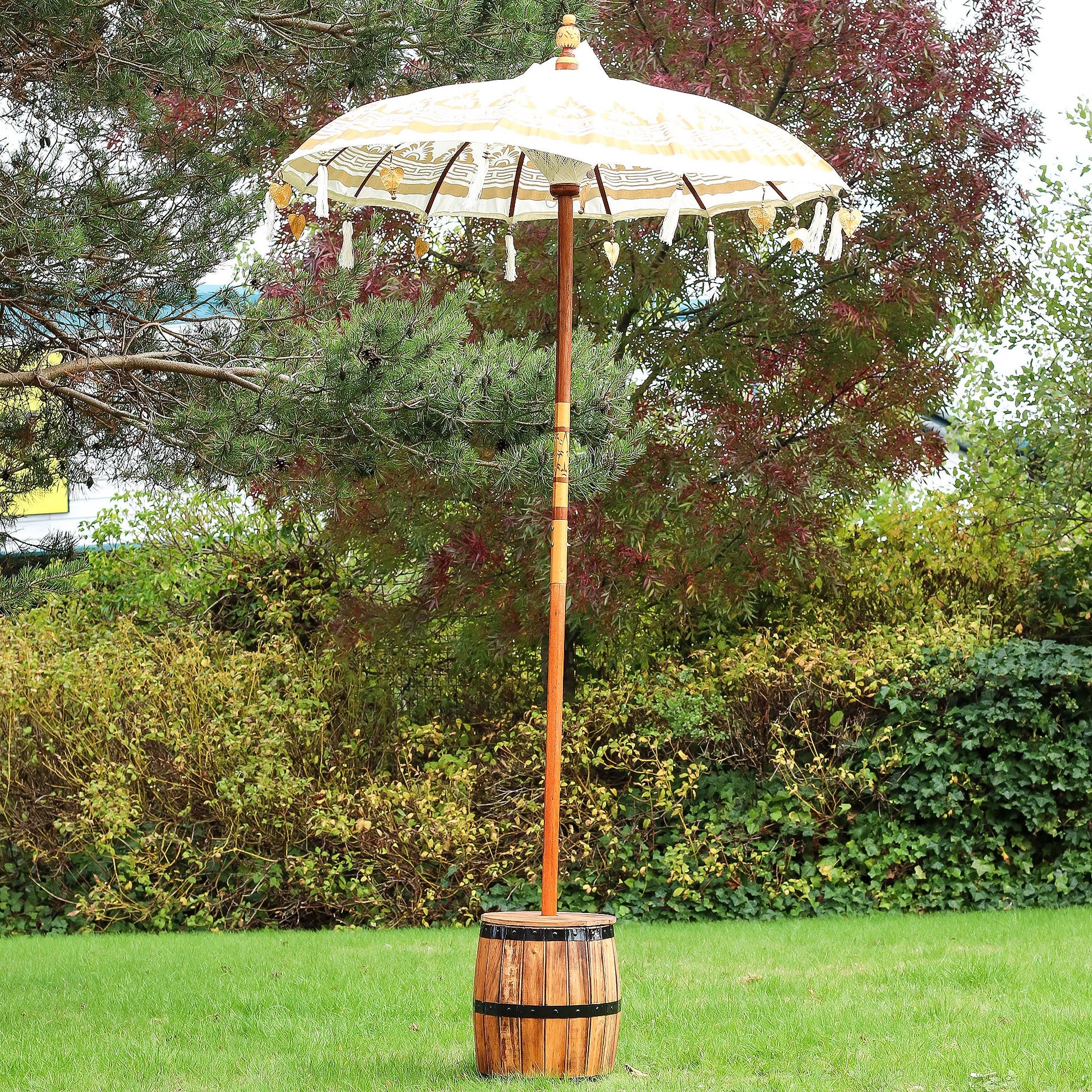Handcrafted Decorative Parasol - Medium - Natural, standing open outdoors with gold trim and dangling ornaments by Quintessential Holistic Health Ltd